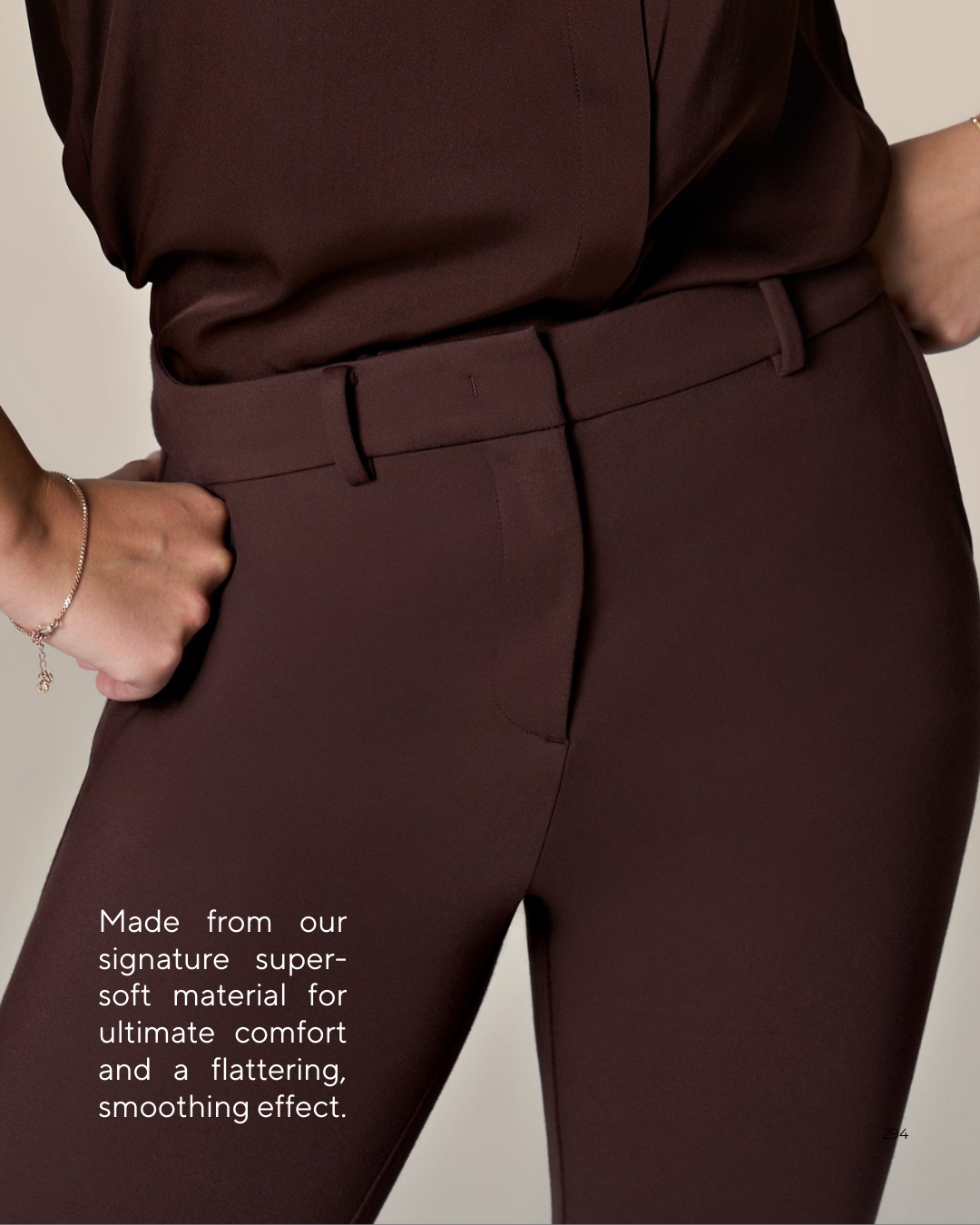 Close-up of a woman wearing a matching brown blouse and pants, with her hands on her hips. Text on the image states: 'Made from our signature super-soft material for ultimate comfort and a flattering, smoothing effect.'