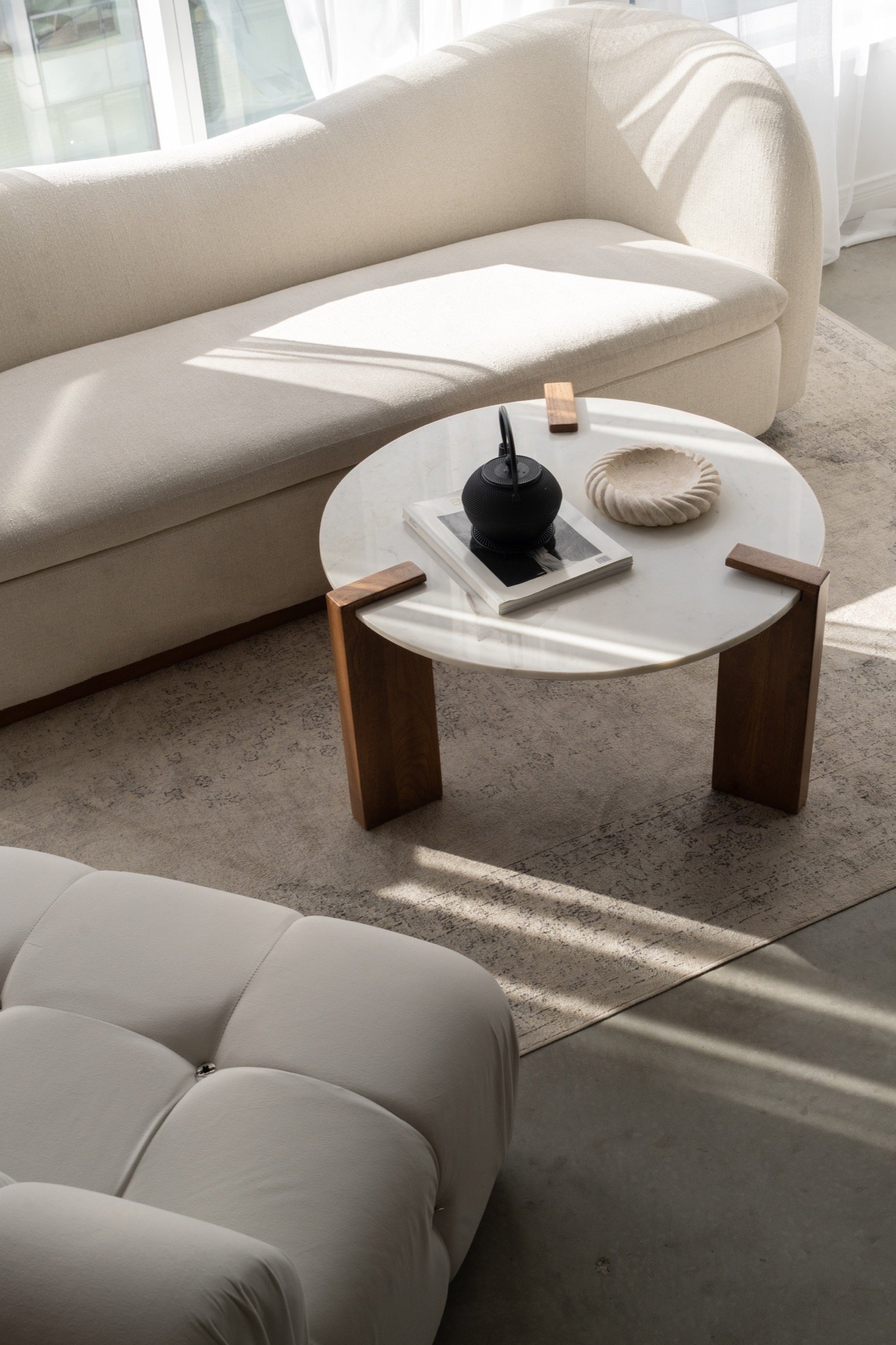 Cream lounge seating and a styled round coffee table in natural light.