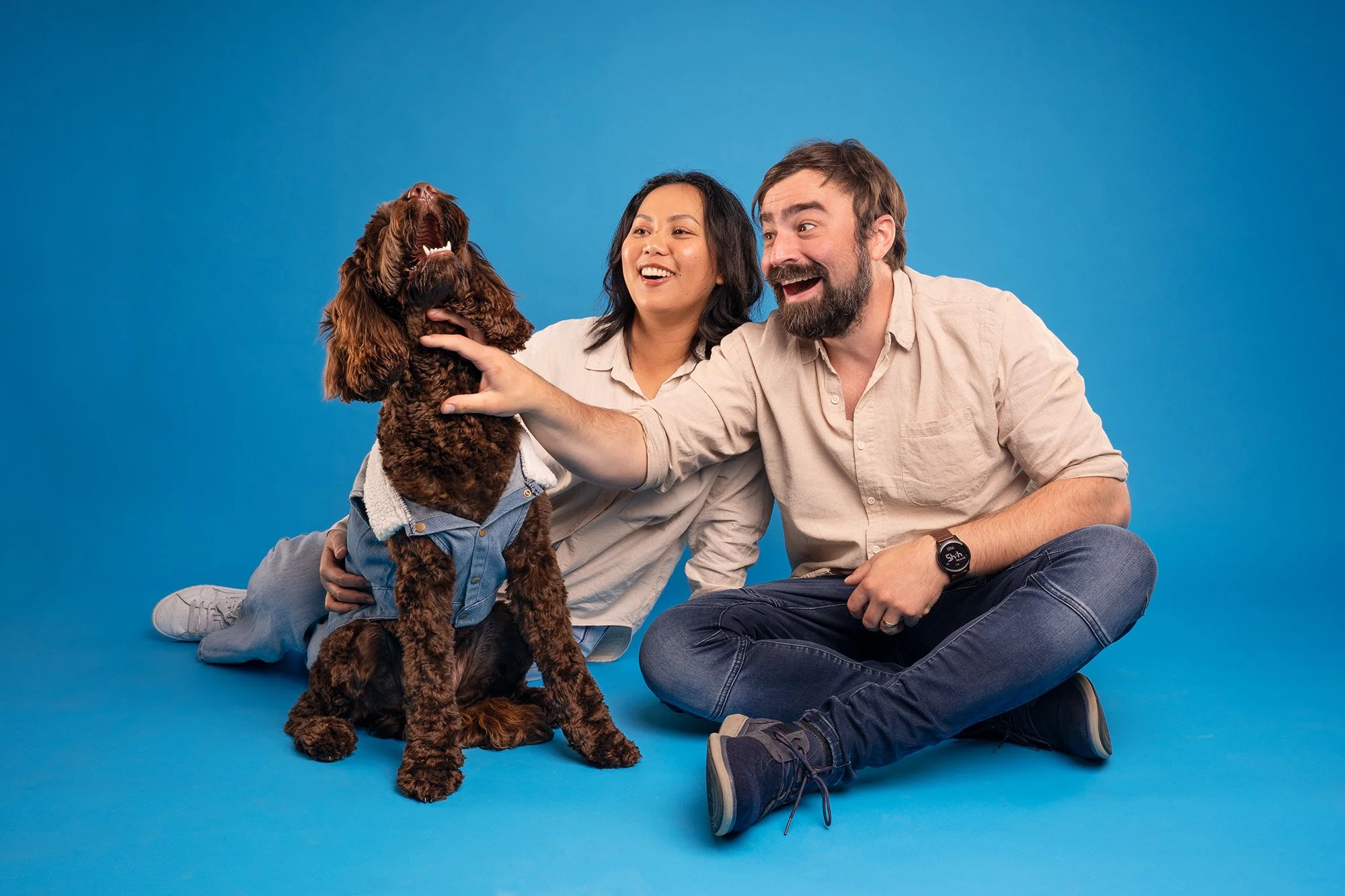 A family sharing a sweet moment with their dog as they give it affectionate scratches during a studio photography session.