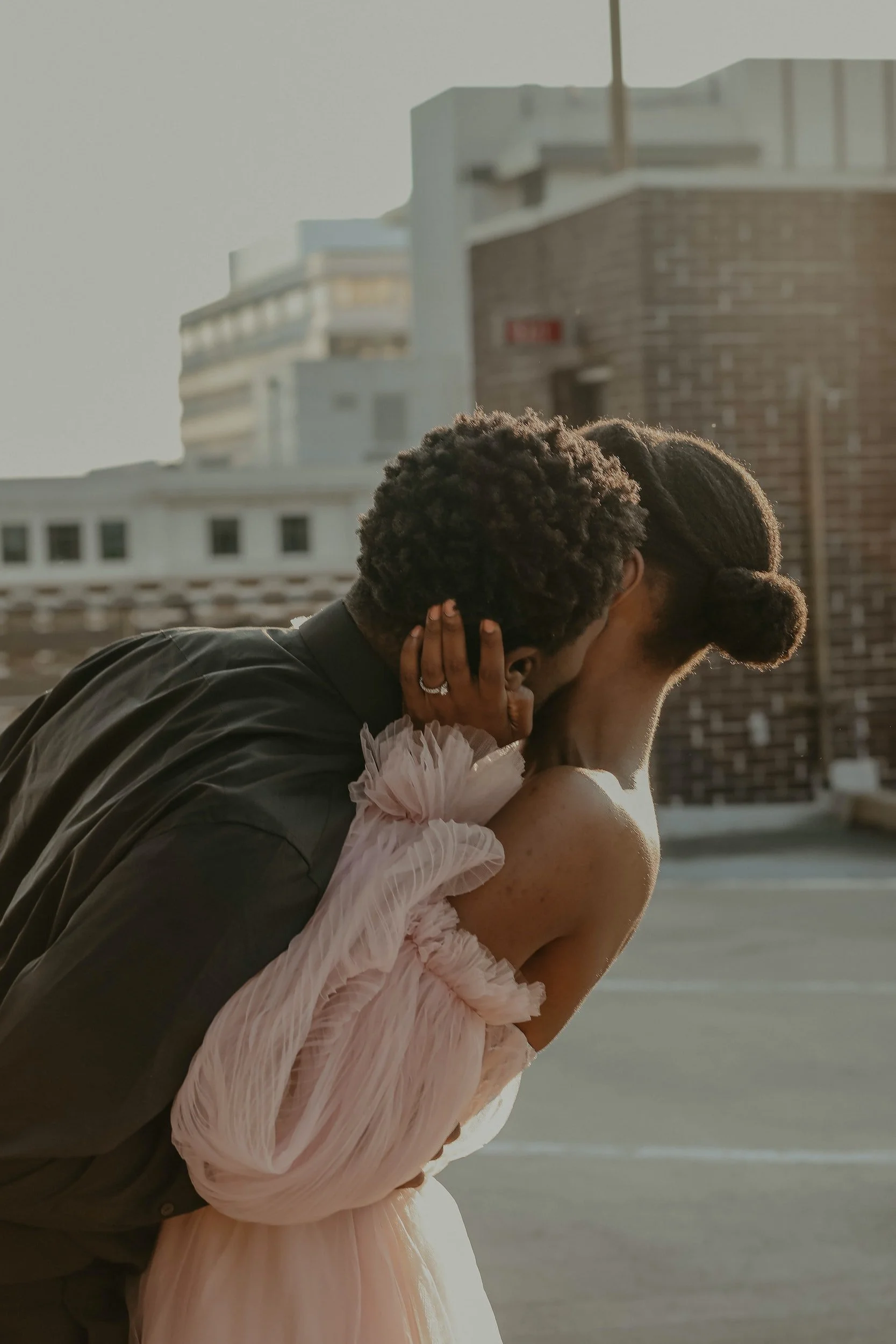 A bride and groom share an intimate hug, while he gives her a kiss on the cheek.
