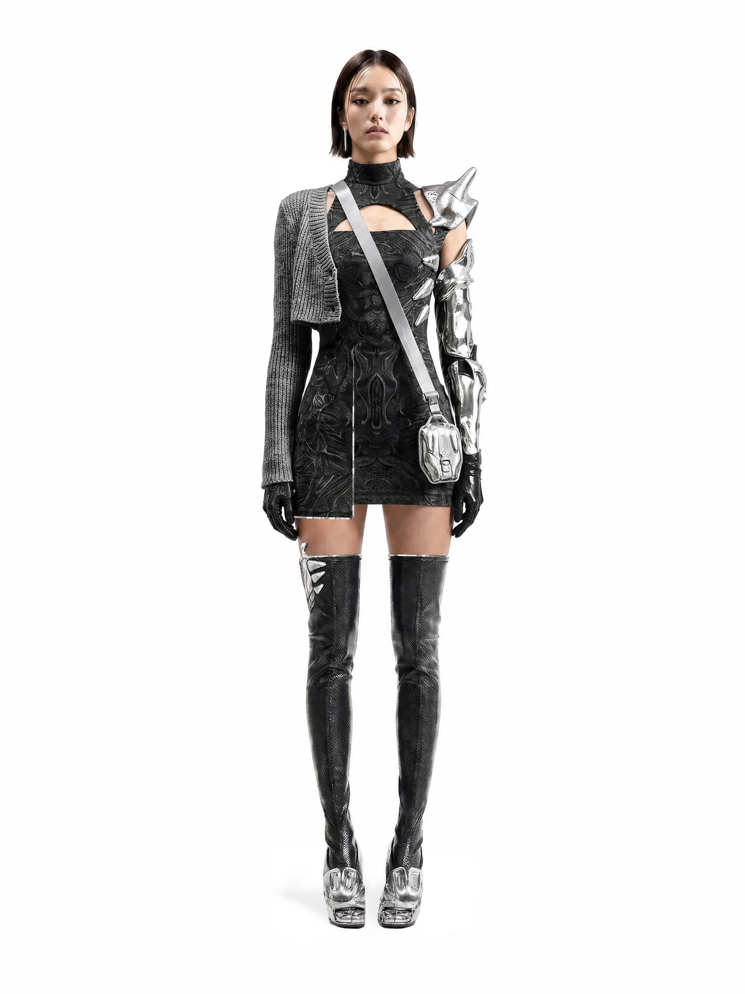 Model and brand ambassador Jun Xeda posing in an editorial photoshoot for digital fashion brand [ze Luna]. She is wearing a bold avant-garde black dress with chrome armor like accessories, with black stockings and a chrome bag and a grey half coat.