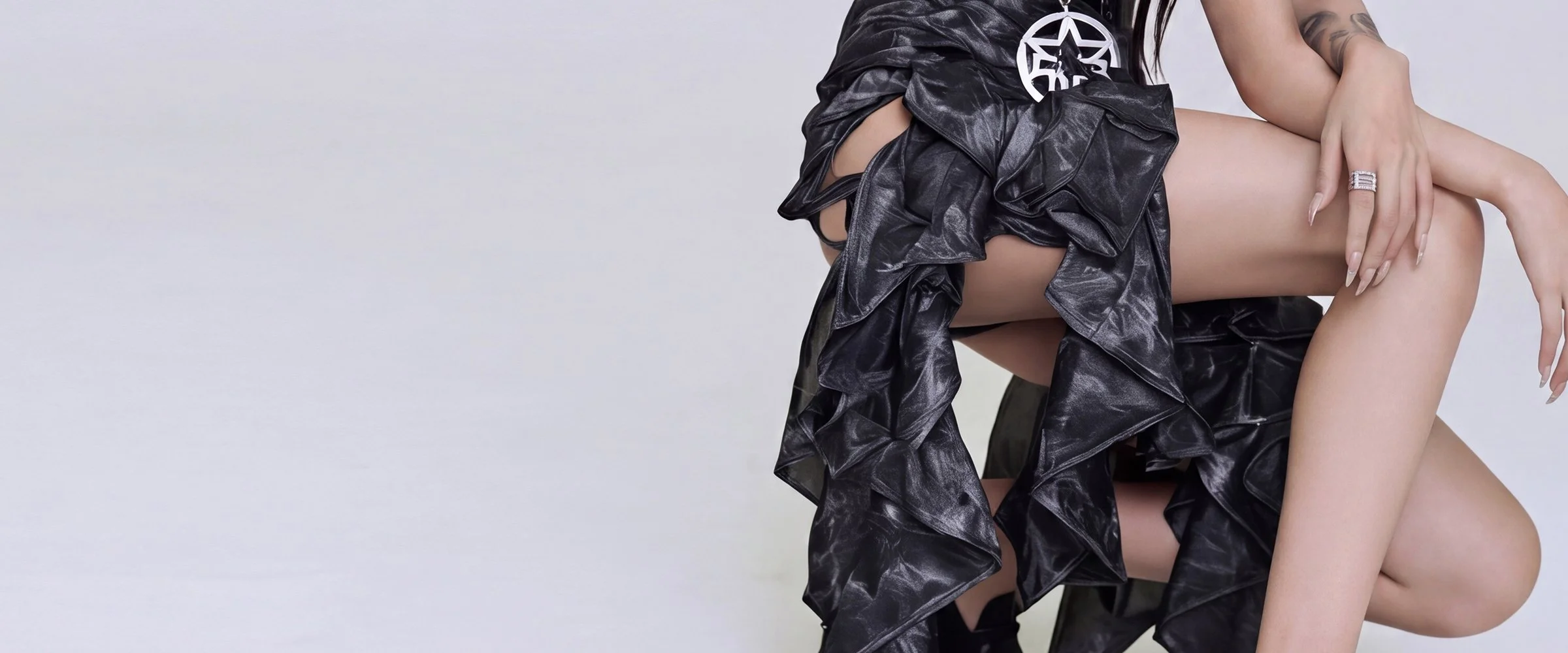 Model Xia Iseri in an avant-garde neo-gothic outfit, fusing streetwear punk aesthetics with high fashion. She is posing in a dynamic manner, with her white sheer crop top, deconstructed ruffled maxi skirt and platform loafers. She looks beautiful and