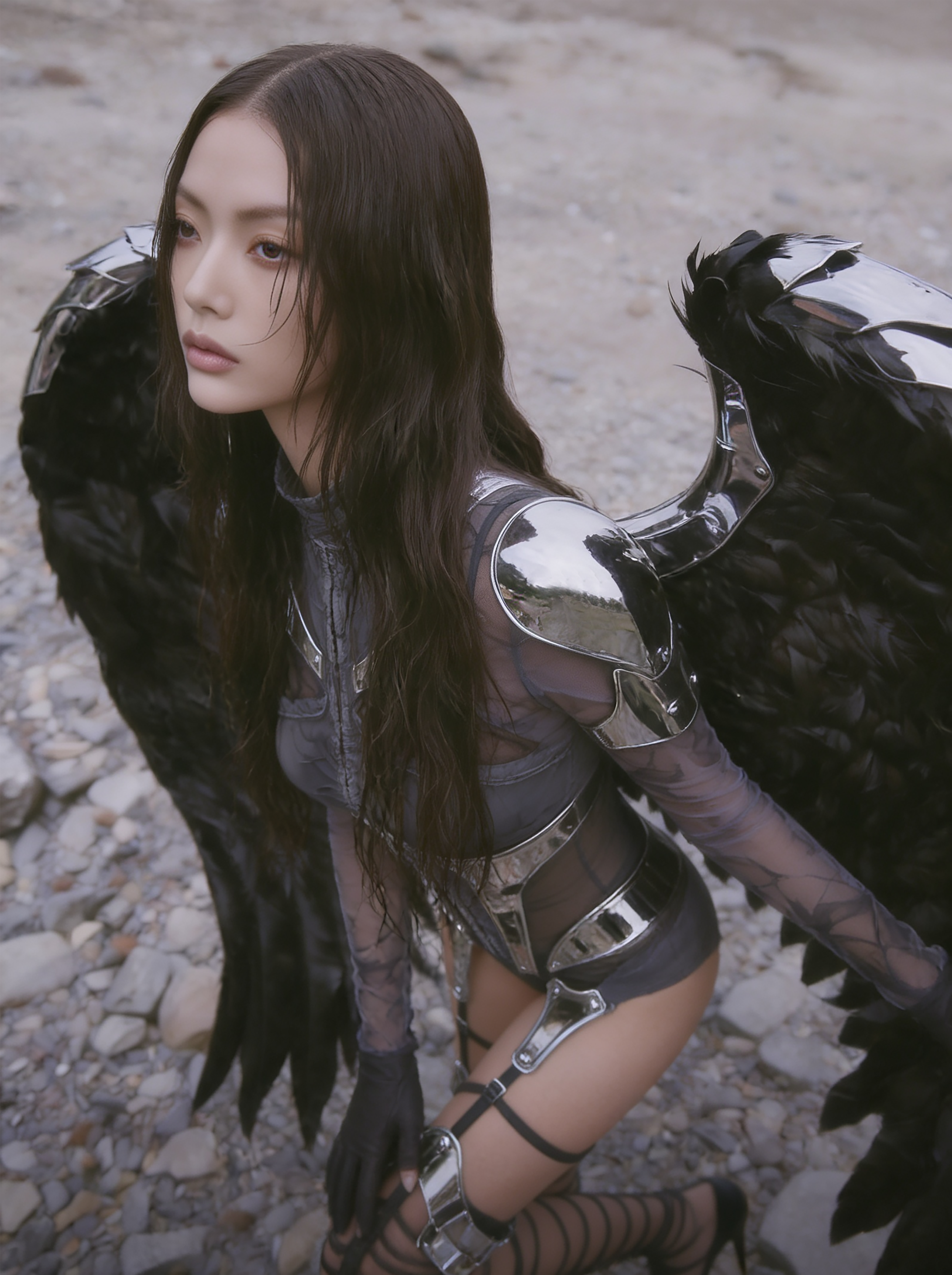 Model Xia Iseri in an otherworldly winged outfit, comprising of chrome and dark fabric, paired with avant-garde laced footwear. The overall vibe of the image exudes an untamed and sovereign energy, inspired by the raven. Outdoor photoshoot.