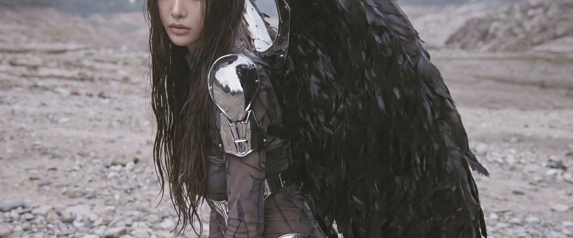 Model Xia Iseri in an otherworldly winged outfit, comprising of chrome and dark fabric, paired with avant-garde laced footwear. The overall vibe of the image exudes an untamed and sovereign energy, inspired by the raven. Outdoor photoshoot for digita