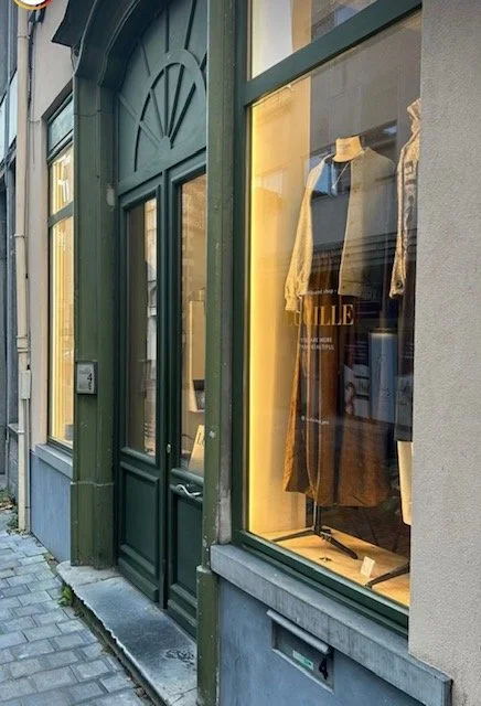 Storefront with large glass window showcasing a dress on display inside.