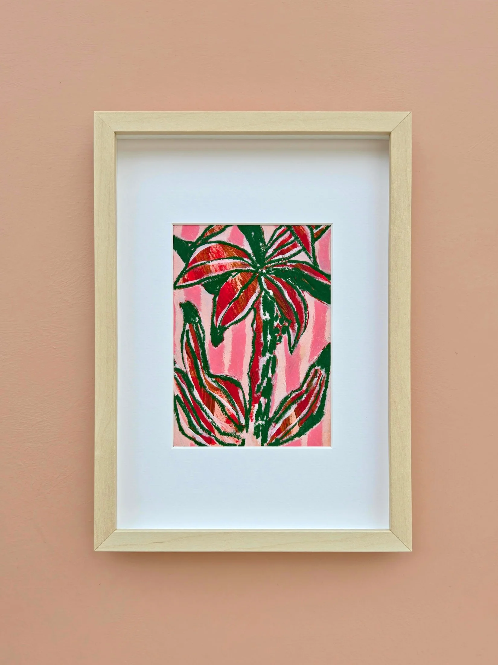 wooden frame on a pink wall, with a colourful palm tree image in it