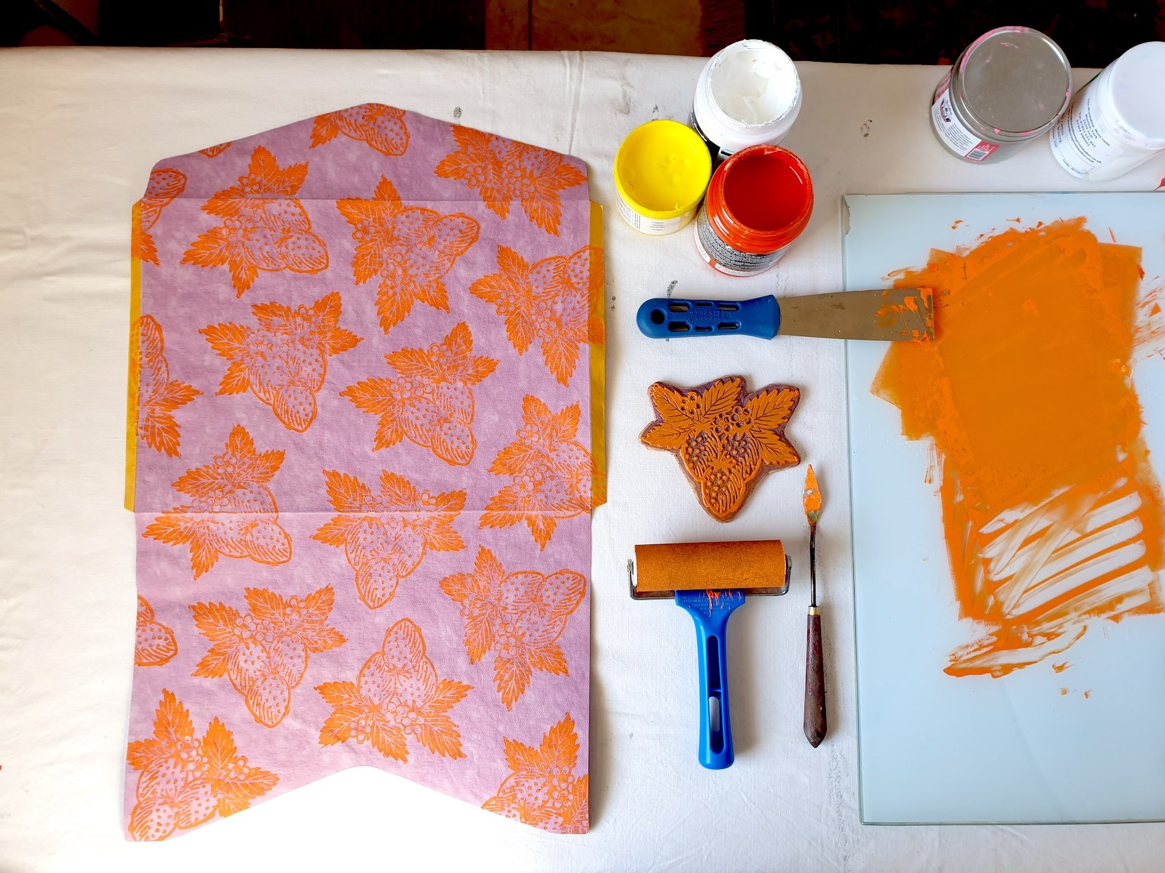 table prepared wih lino printmaking material, including, brayer, inks, palette knife and glass palette