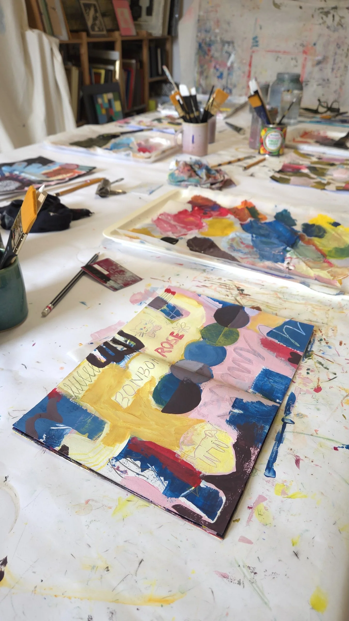 open sketchbook with colourful pages and palette and brushes