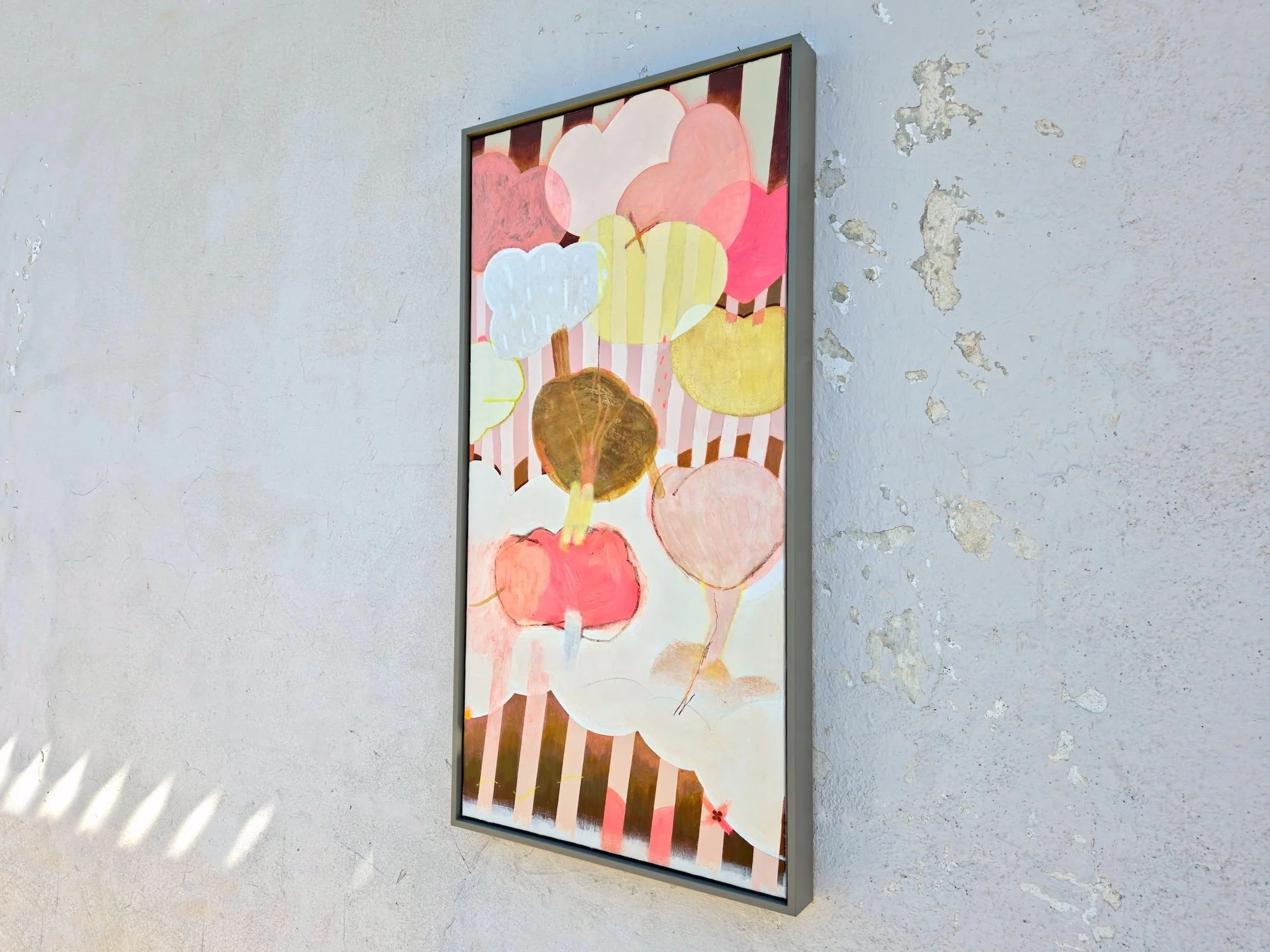 angled view of framed botanical painting in pinks and browns with bold stripes