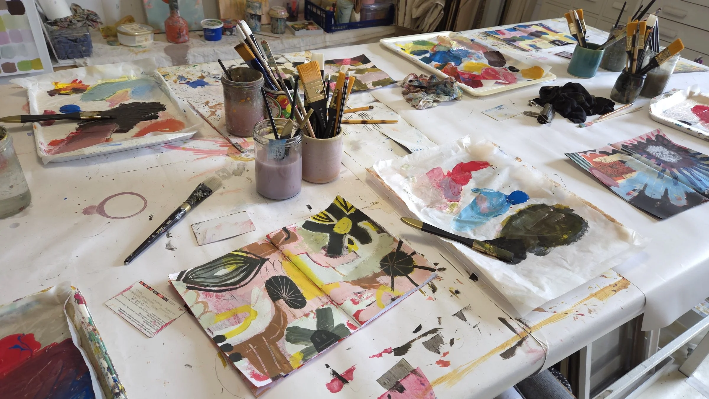 painting workshop table with art material and open sketchbooks