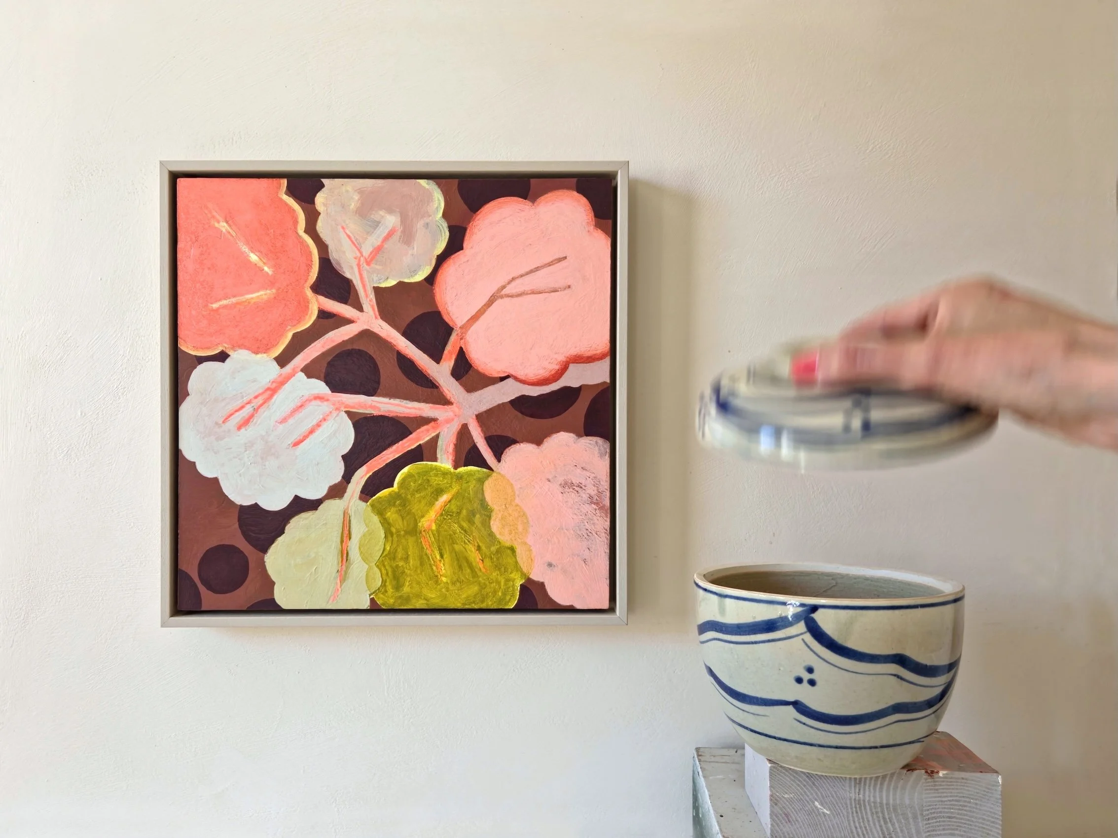 framed botanical painting in pinks, beige and browns next to a ceramic pot