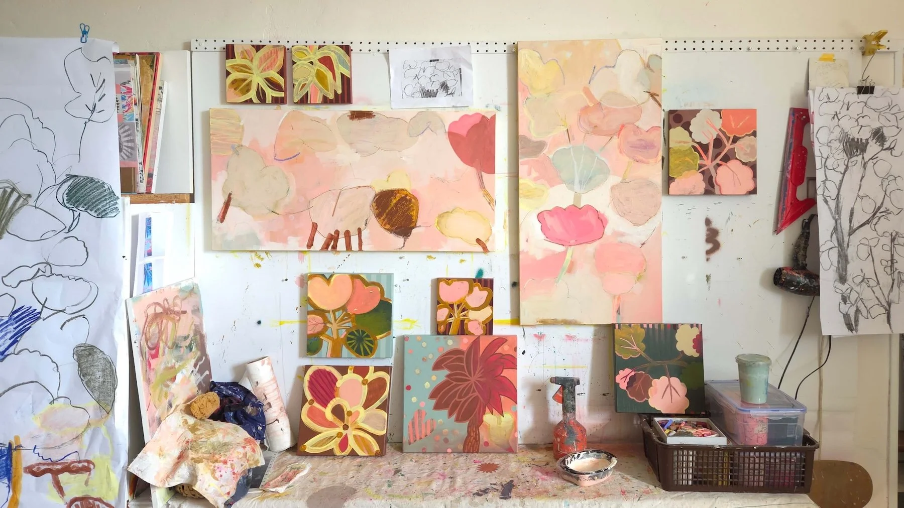 wall covered with canvases of botanical subject with paint drips