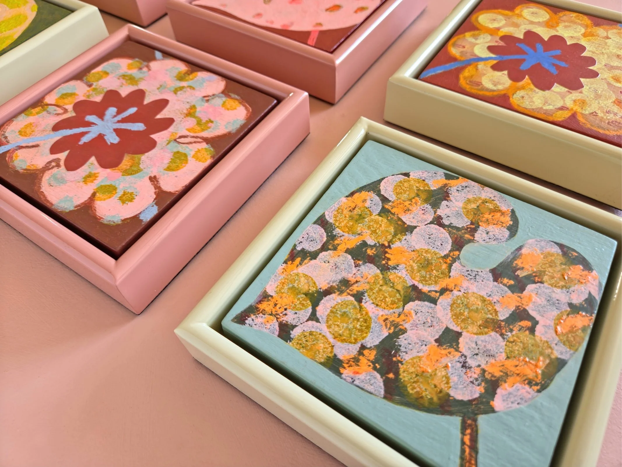 detail of small framed botanical paintings on a pink background