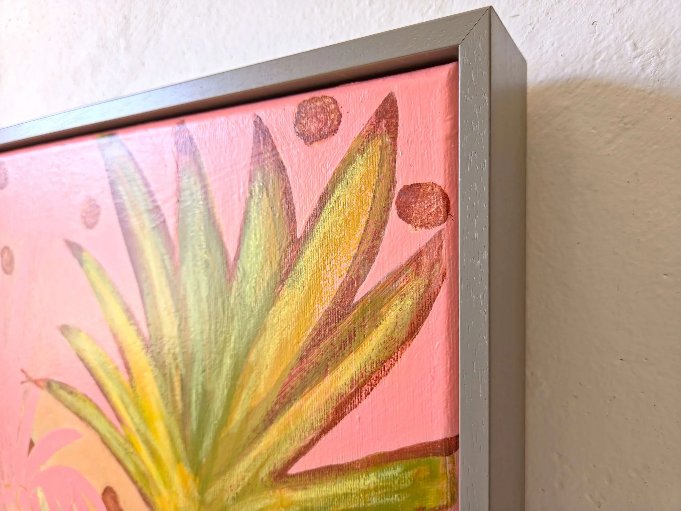 detail of framed palm tree painting on a vibrant pink background