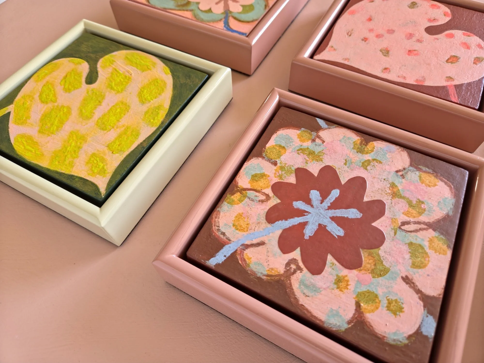 detail of small framed botanical paintings on a pink wall