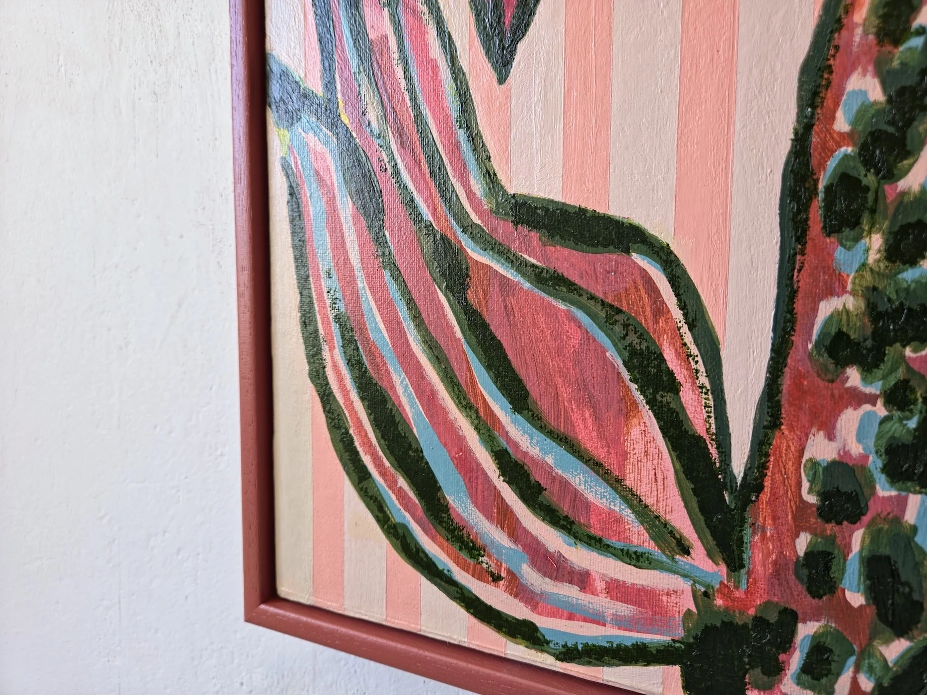 detail of framed palm tree painting with pink stripes background