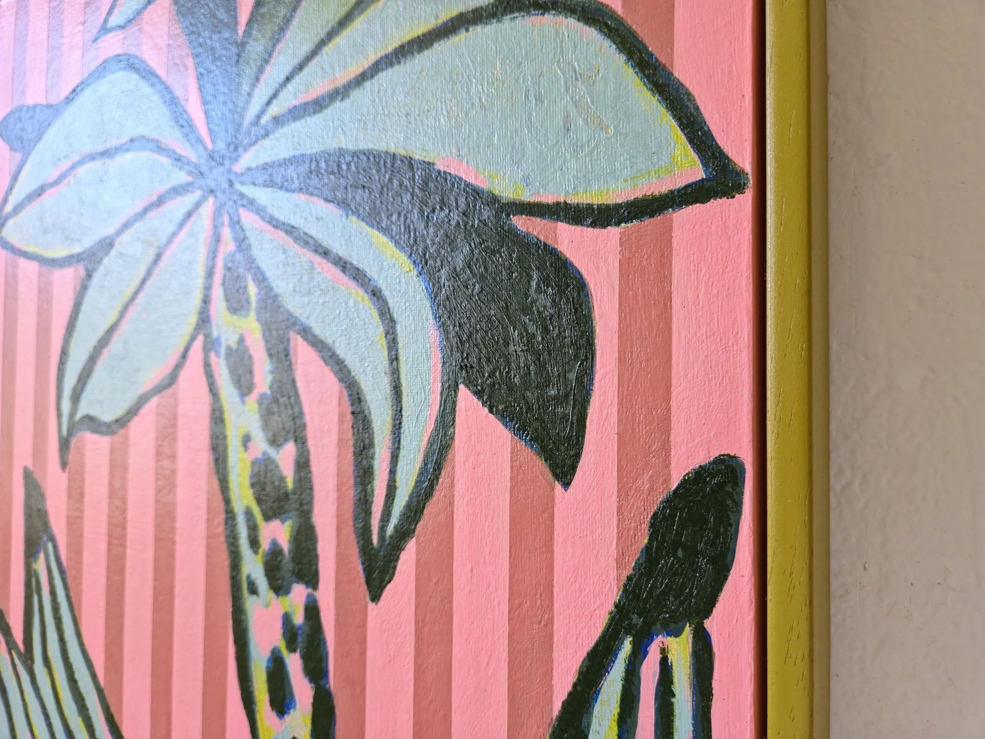 detail of framed palm tree painting with pink striped background