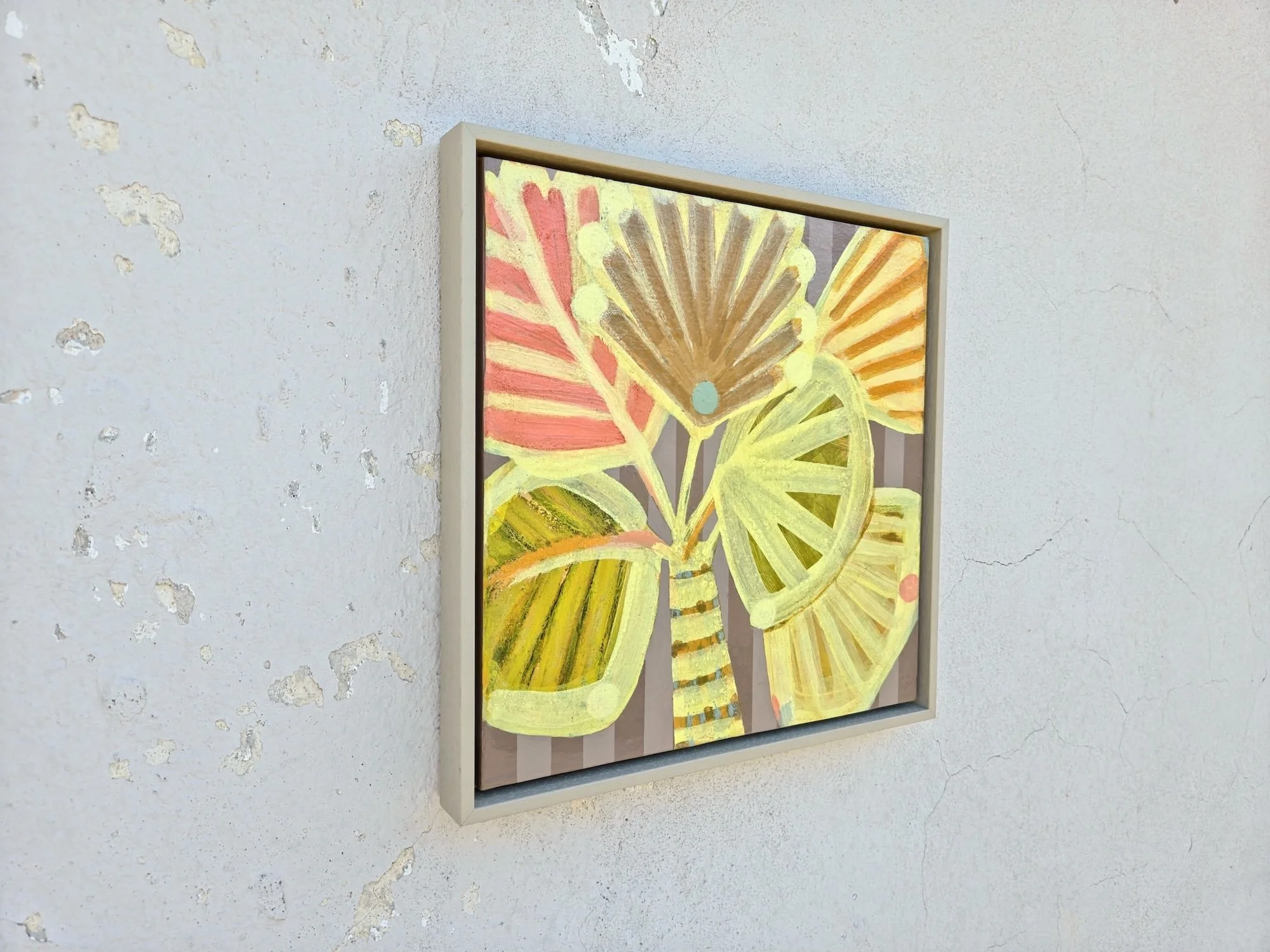 angled view of framed palm tree painting in bright yellows and pinks