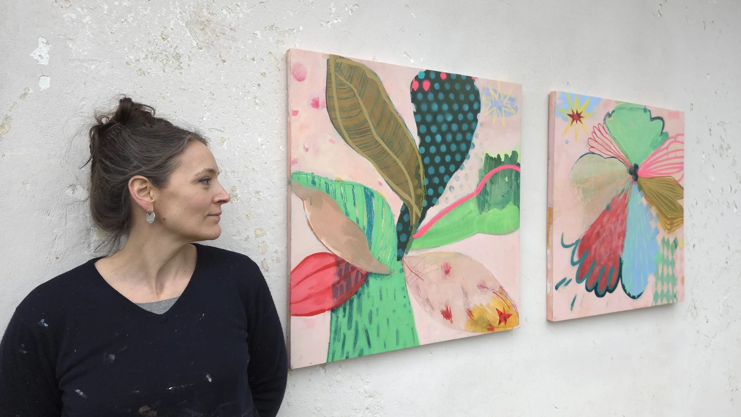 artist leaning on a wall where two colourful palm tree paintings are hanged