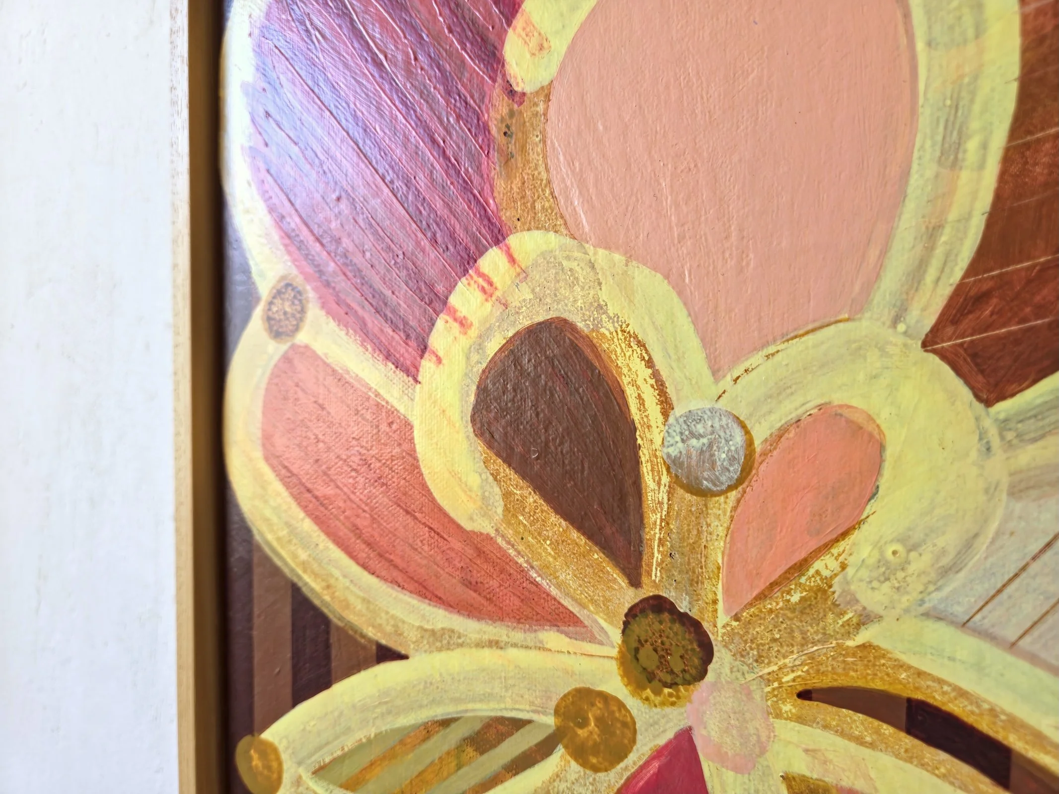 detail of framed botanical painting in yellows and pinks on a striped background