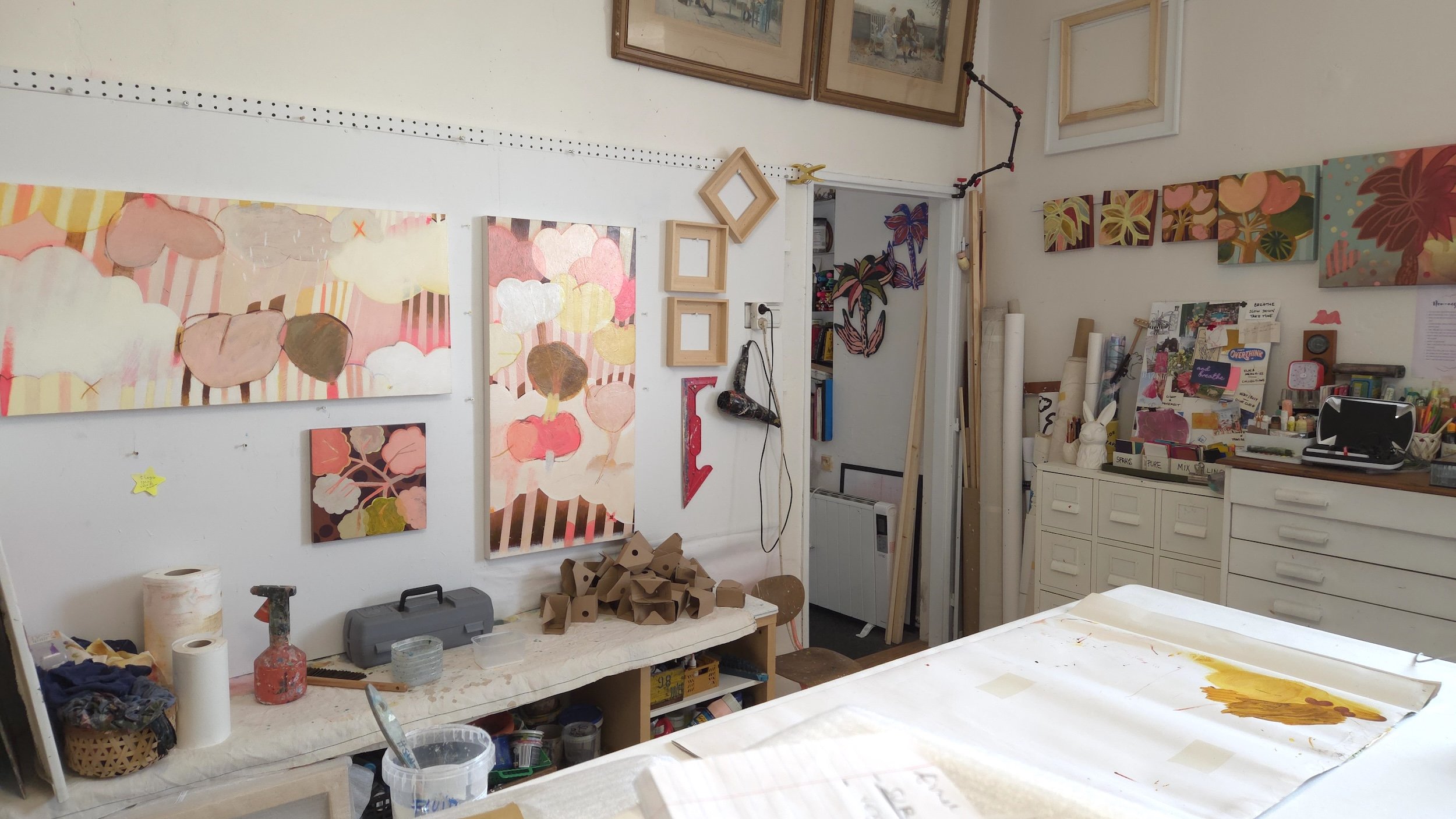 artist studio with walls full of colourful canvases and art making tools