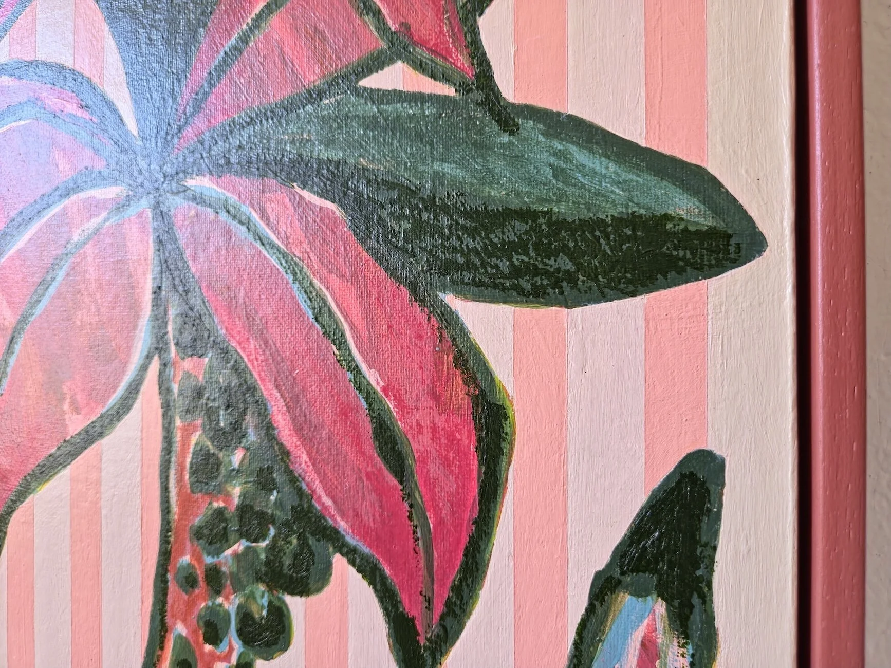 detail of framed palm tree painting with pink stripes background