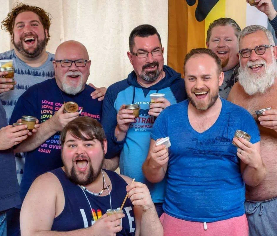 Group of men smiling holding jars