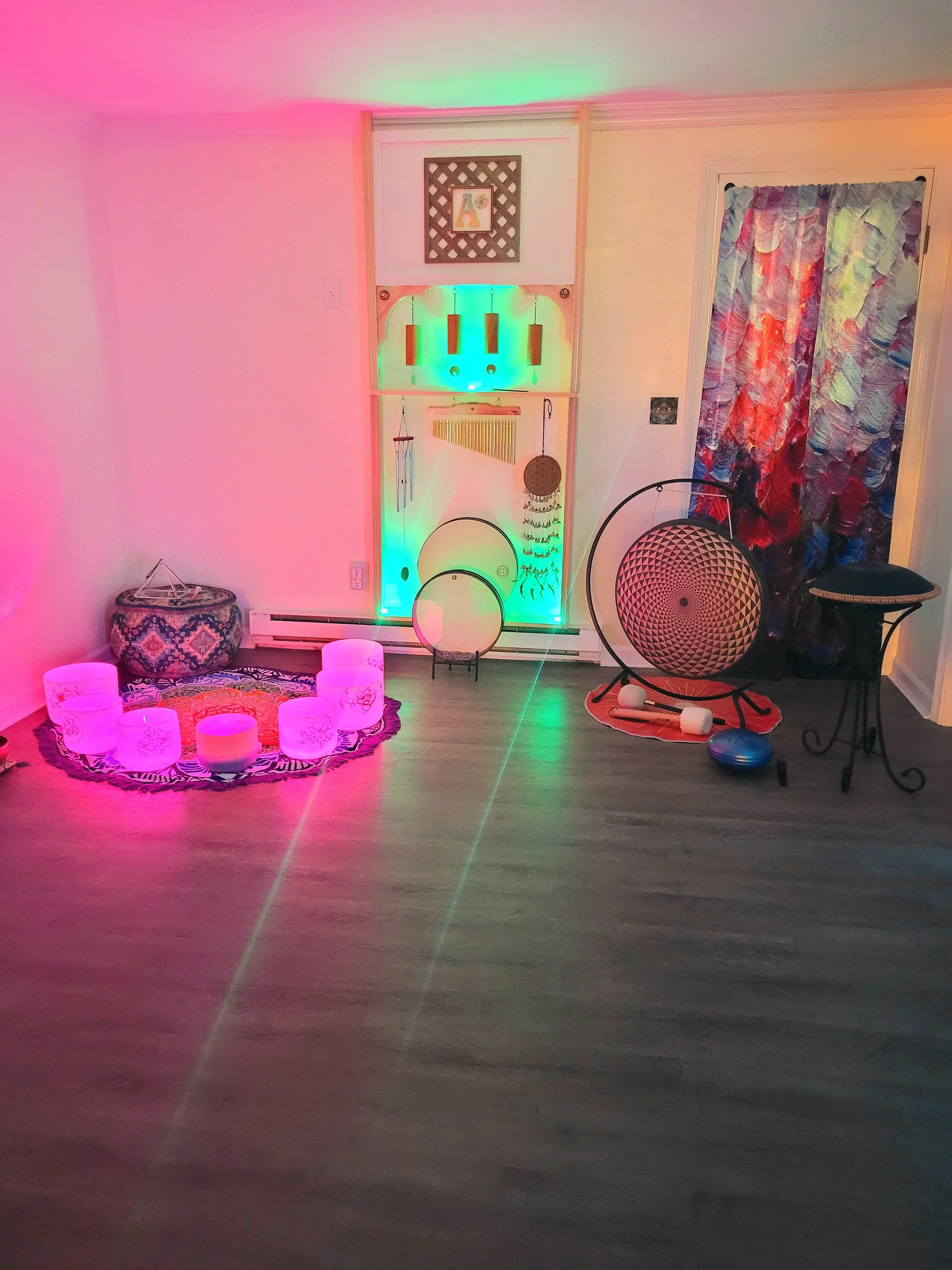 Decorative corner with colorful LED lights, hanging wind chimes, a tapestry with vibrant brushstrokes, and patterned furniture, creating a cozy, artistic ambiance.