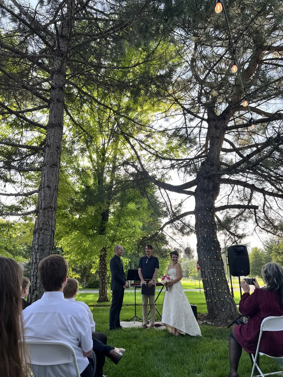Outdoor wedding ceremony beneath the mature trees at Old Town Hall in Huntsville, Utah