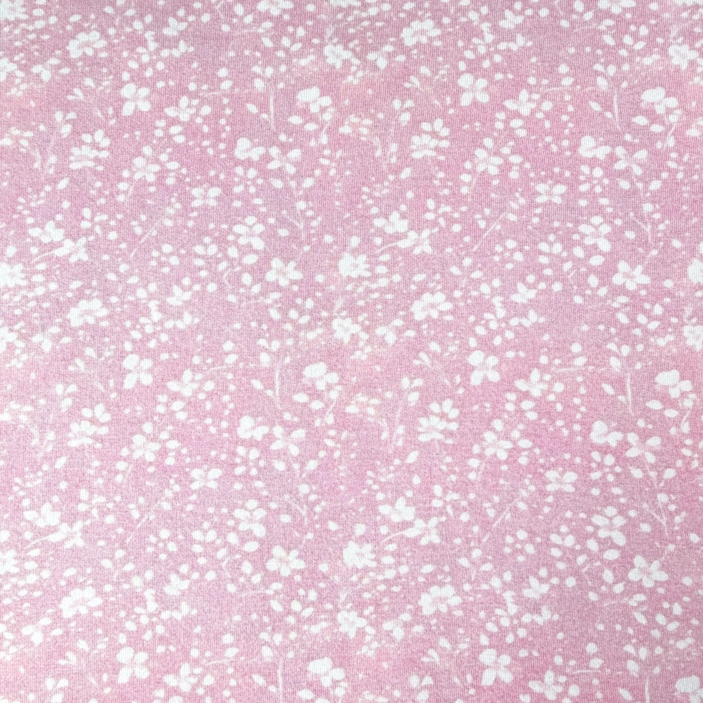 Close-up of pink fabric with white floral pattern.