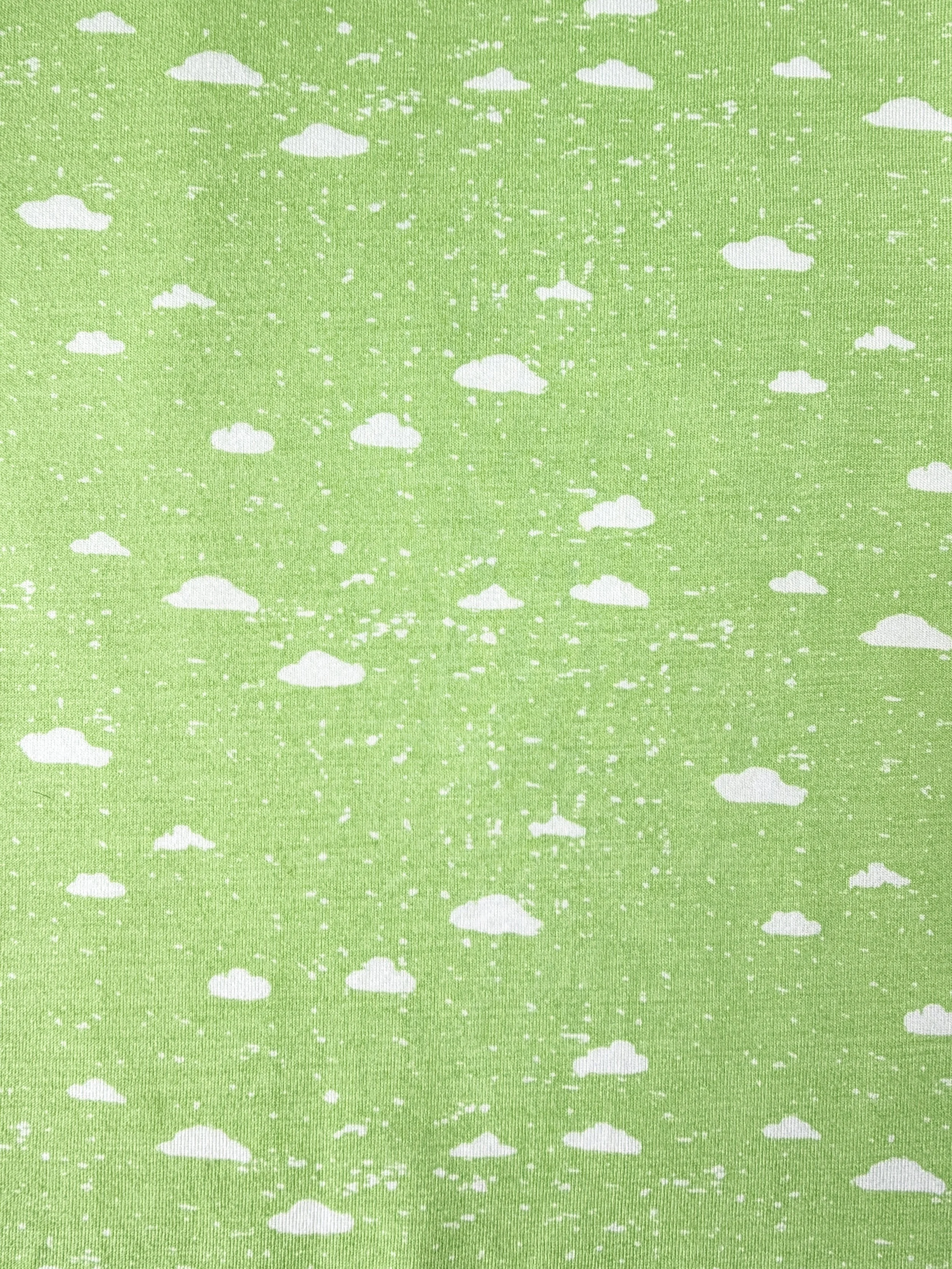 Close-up image of a green fabric with a pattern of white clouds and small white dots.