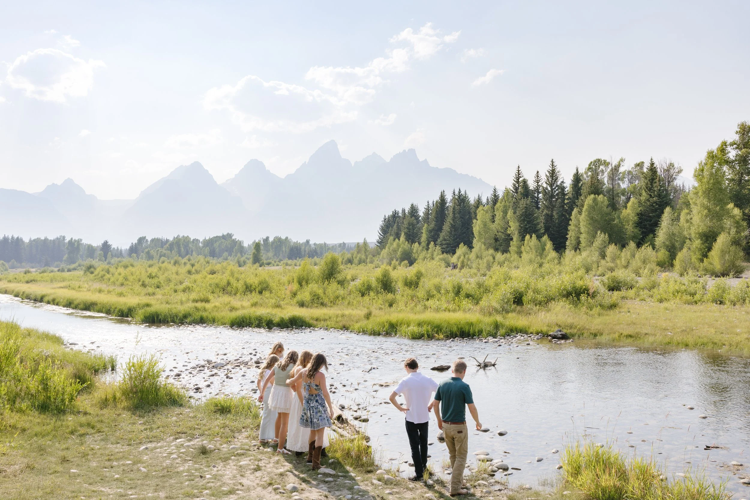 family throwing rocks into the stream during their summer family photos