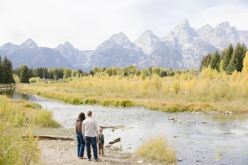Family standing by a river overlooking the Tetons captured by a Jackson WY photographer