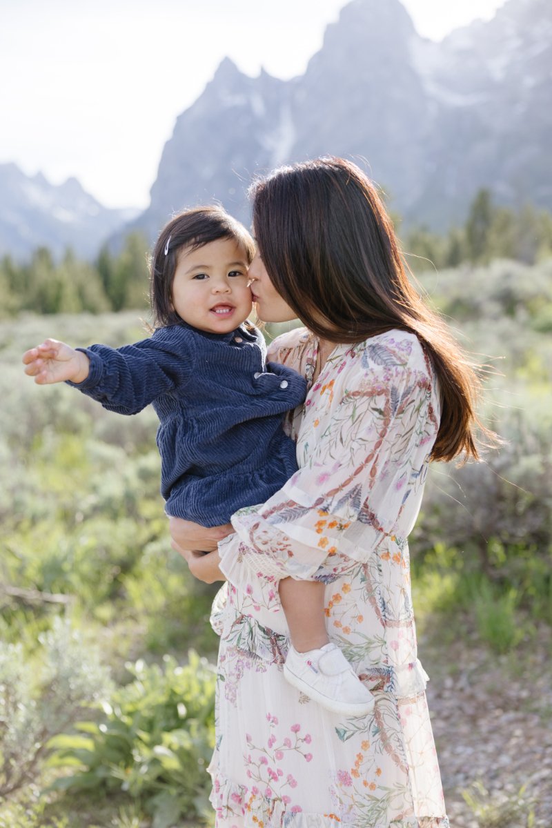  Mother holds daughter with mountain in the background as her photographer shares tips for family photos with young kids. 