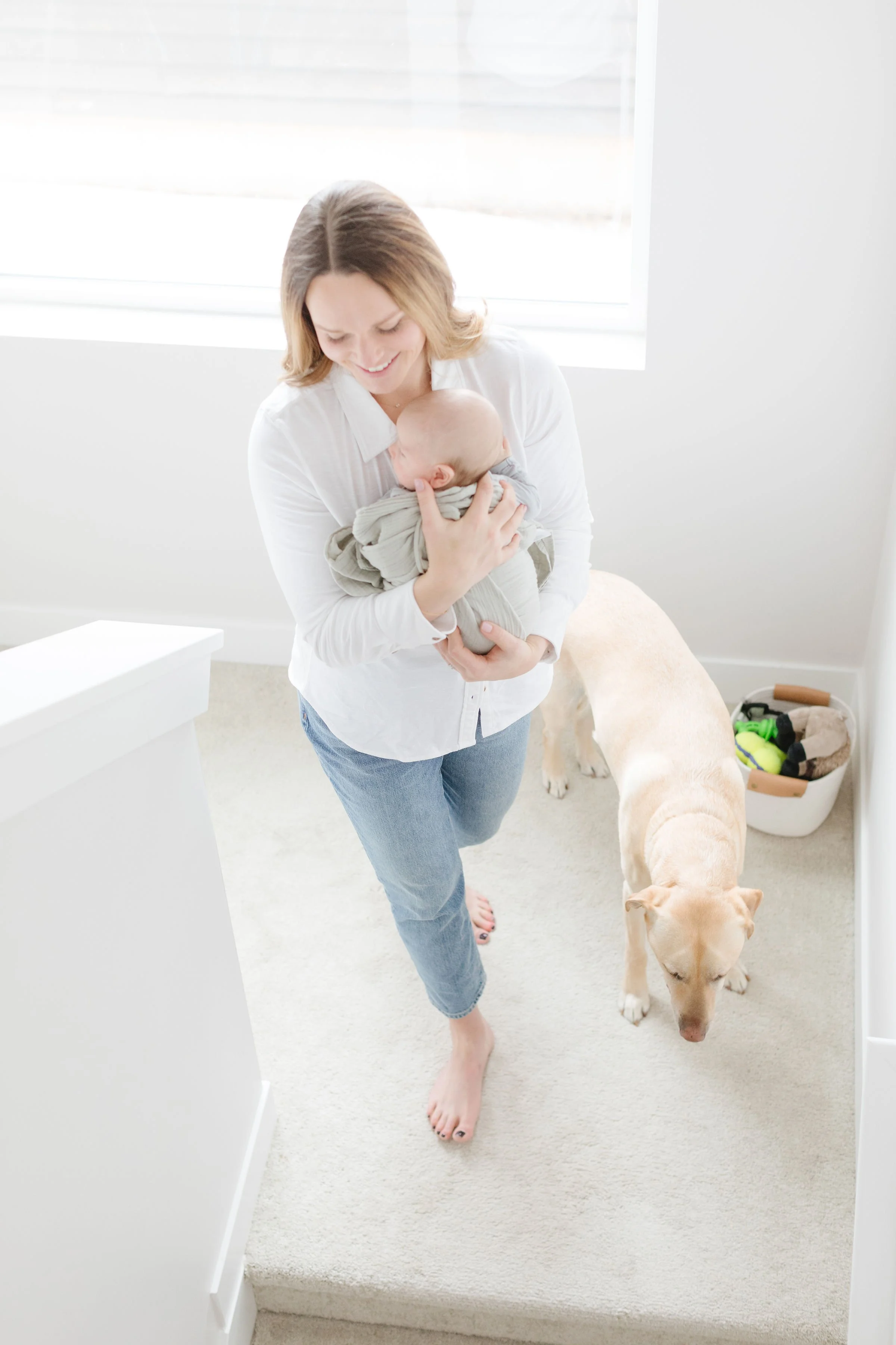  Mom walking down steps holding newborn, with dog walking next to her. 