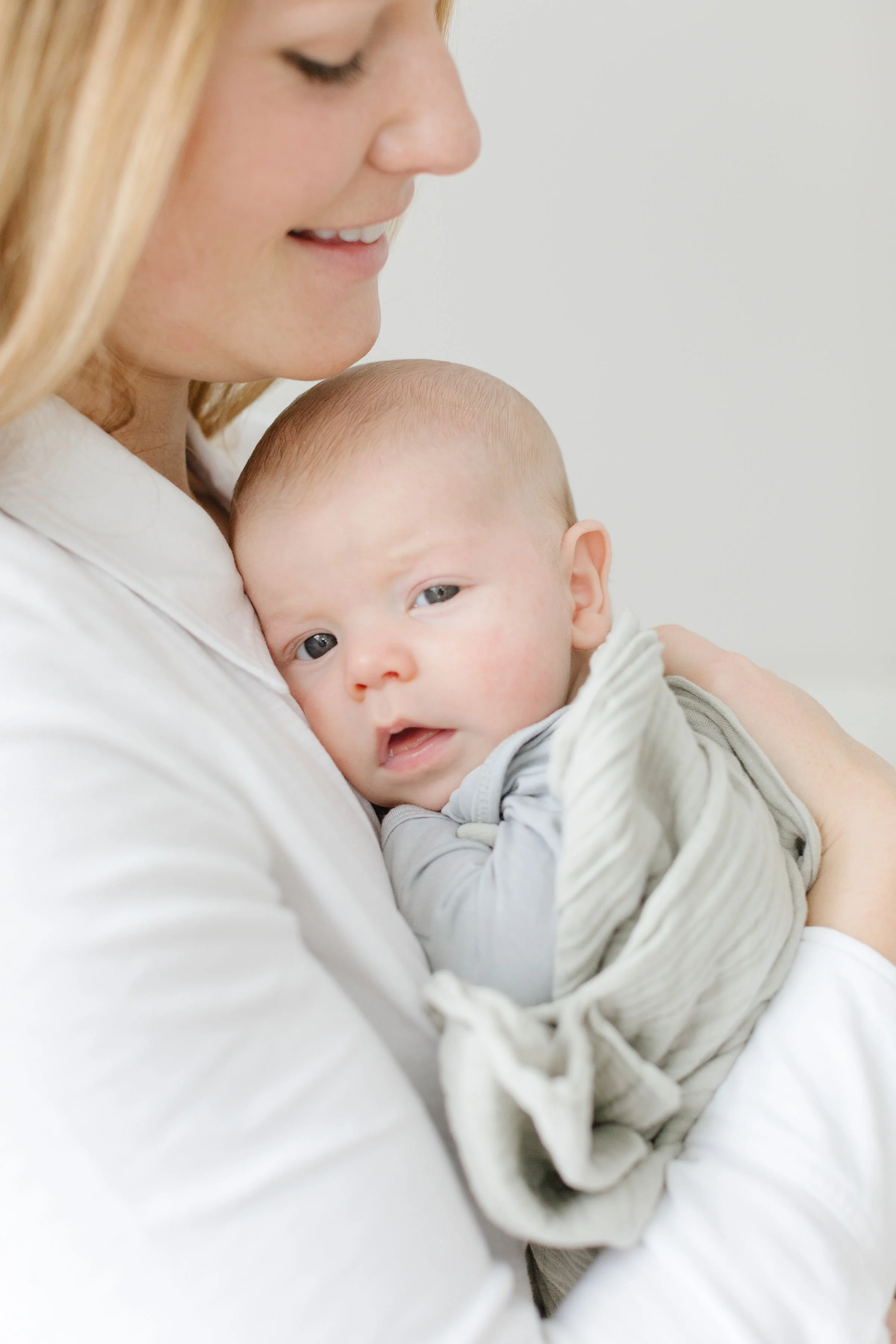  Mom holds baby tight to her chest as newborn photographer in Jackson Hole captures them.  