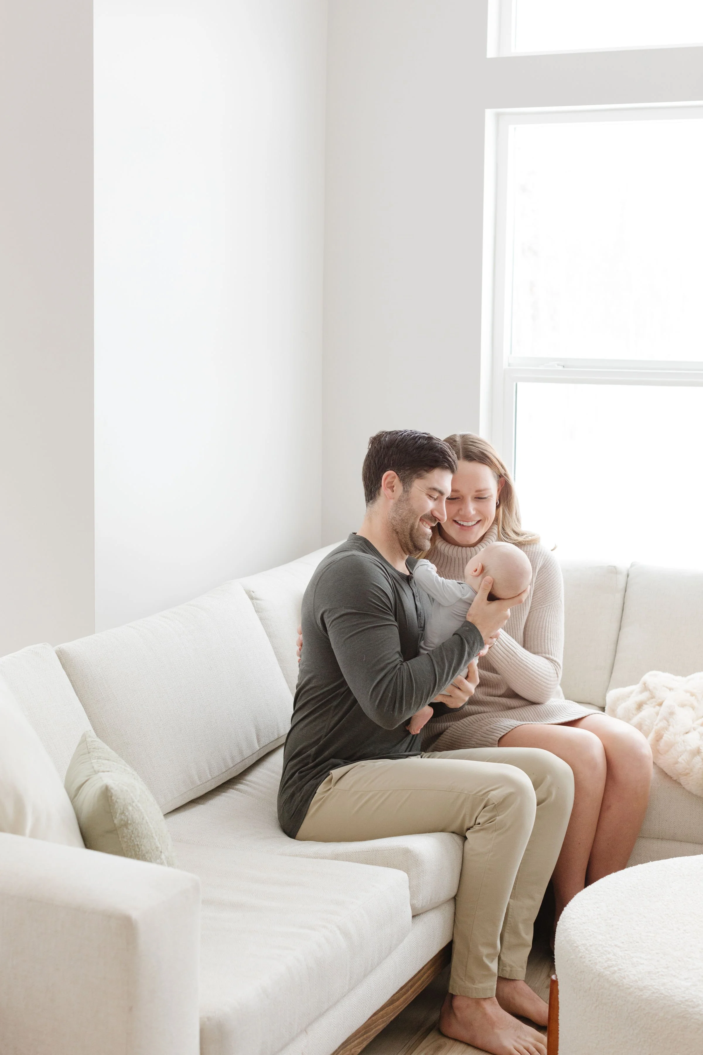  Mom and dad hold baby as newborn photographer in Jackson Hole captures them in their living room.  