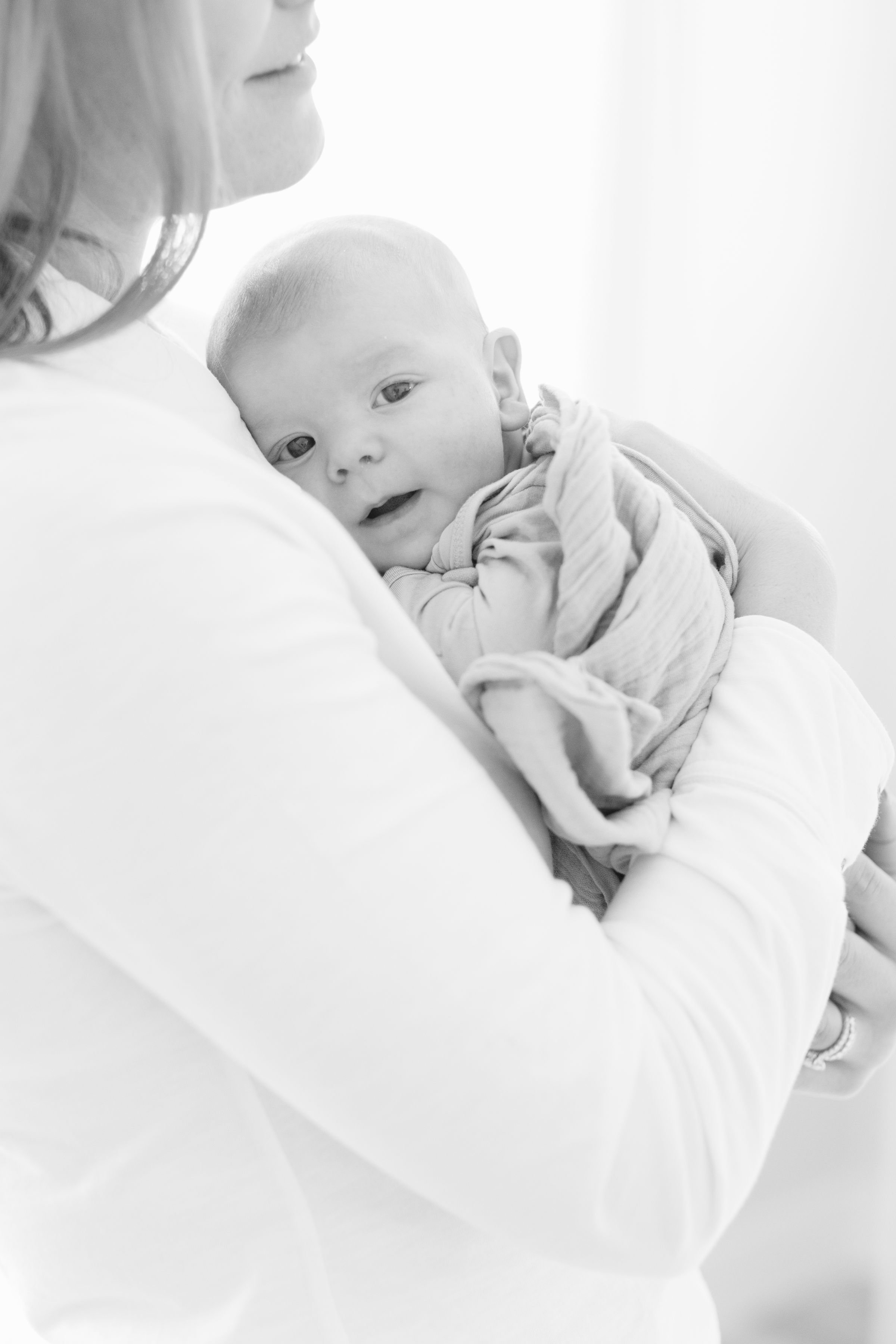  Mom holds baby close to her as newborn photographer in Jackson Hole captures them. 