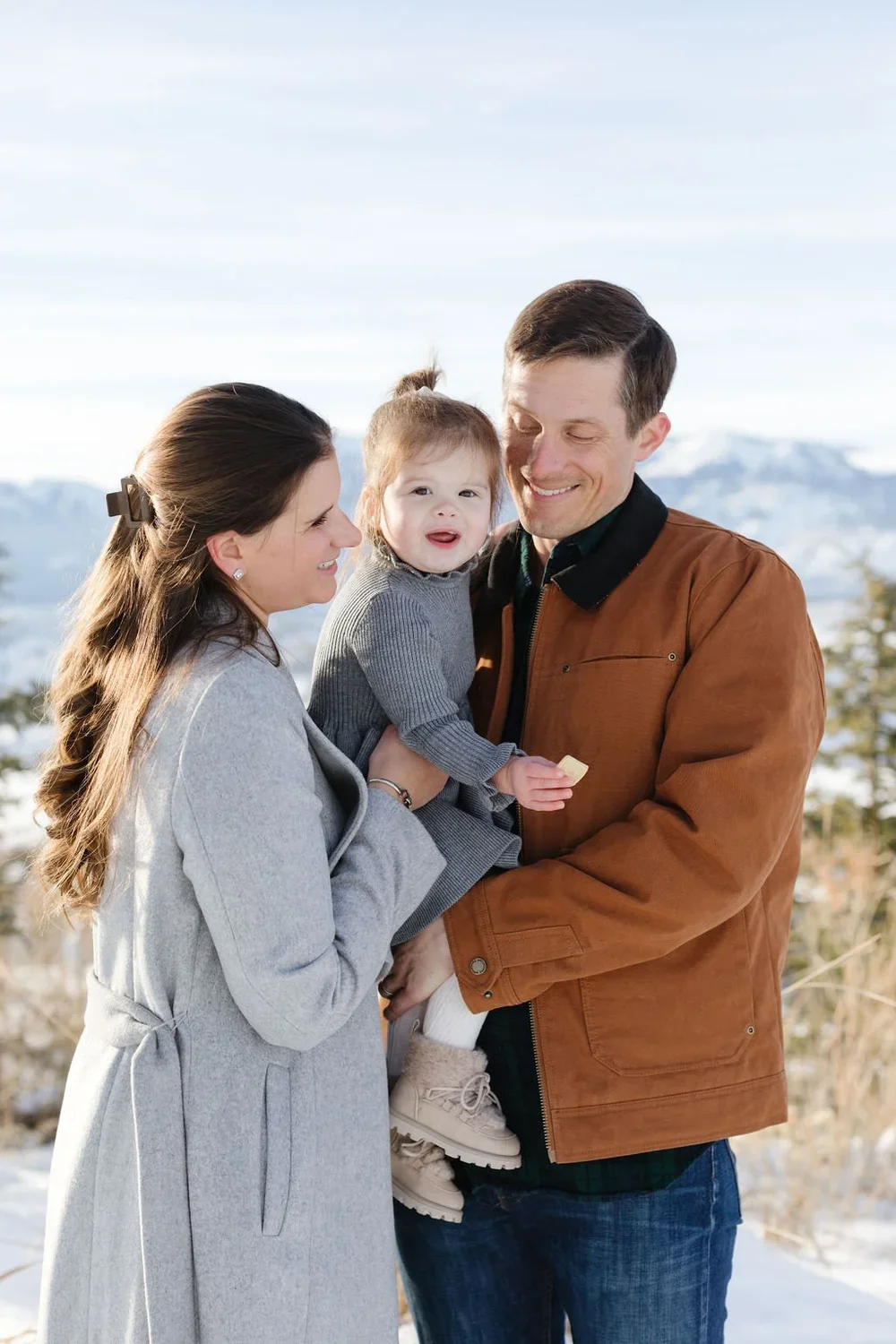  Mother and father hold their daughter during a winter photoshoot. 