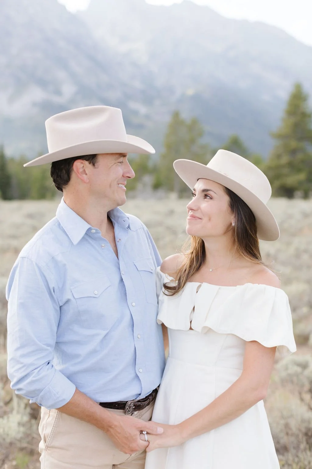  Man and woman smile as they look at each other, happy after a thoughtful date planning in Jackson Hole. 
