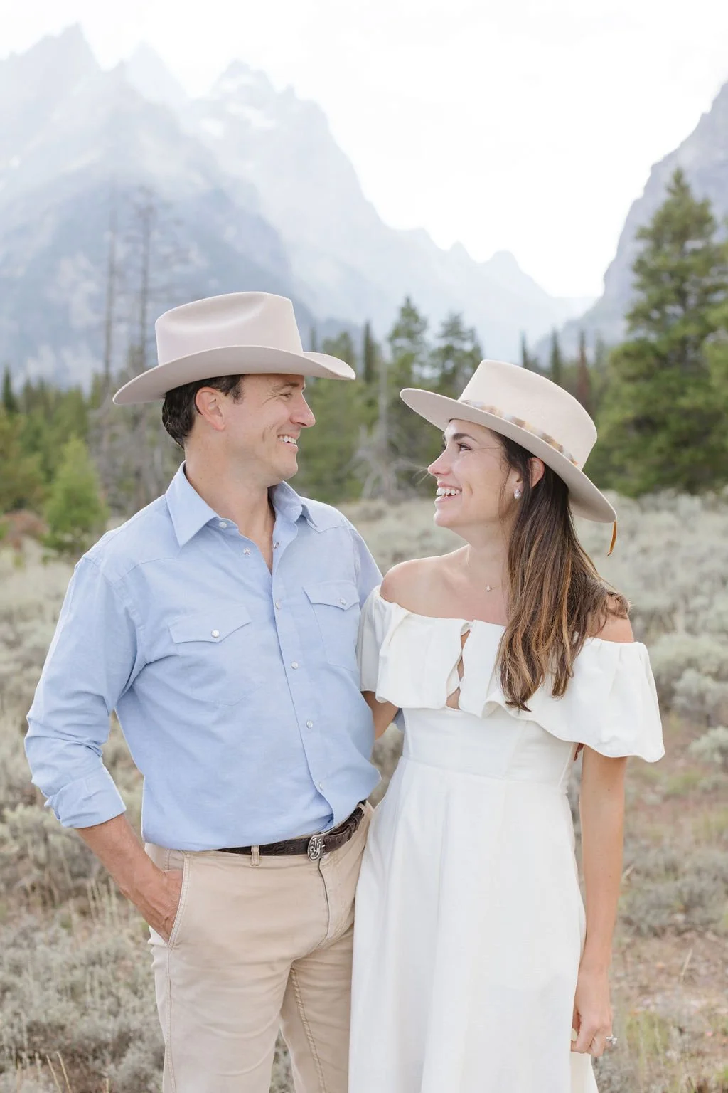 Man and woman smile as they look at each other, happy after a thoughtful date planning in Jackson Hole. 