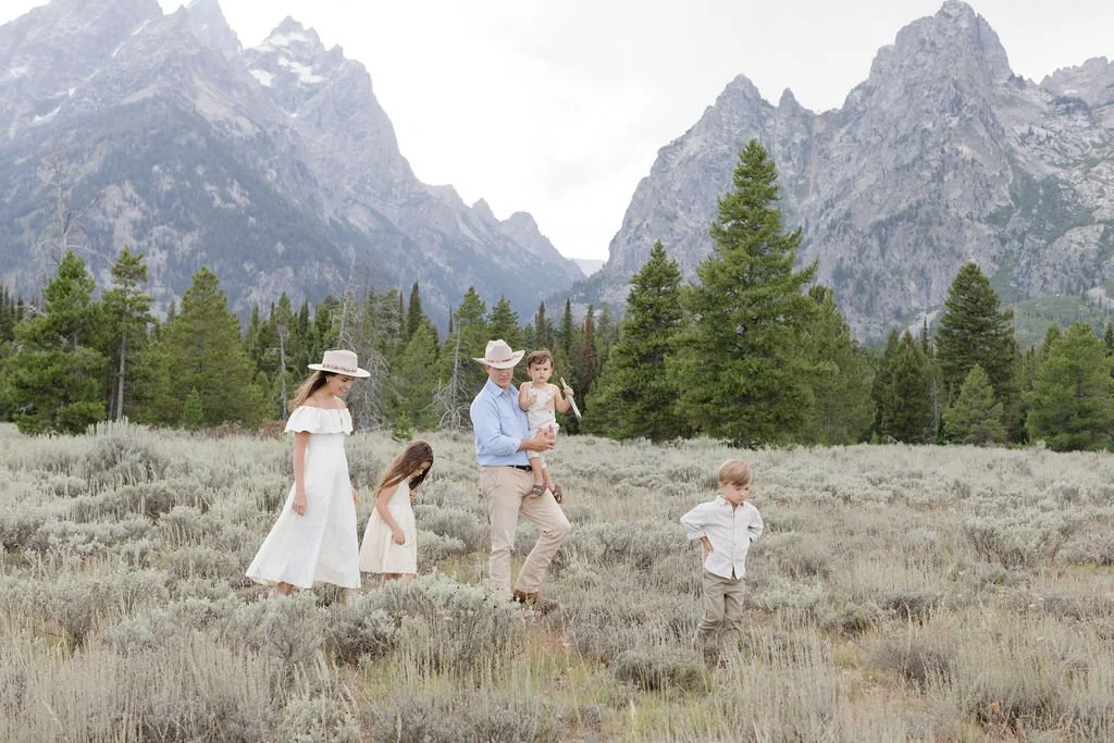  Family walks together through field in the Tetons. 