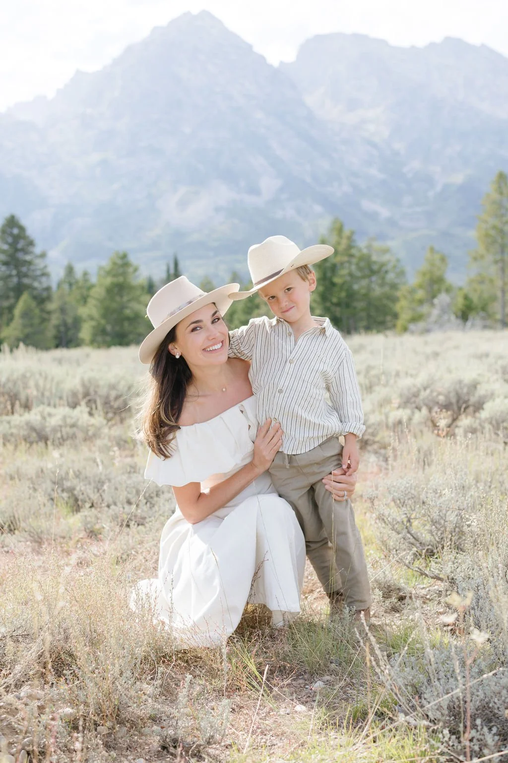  Mother bends down to pose for family photos with her son in the Tetons. 