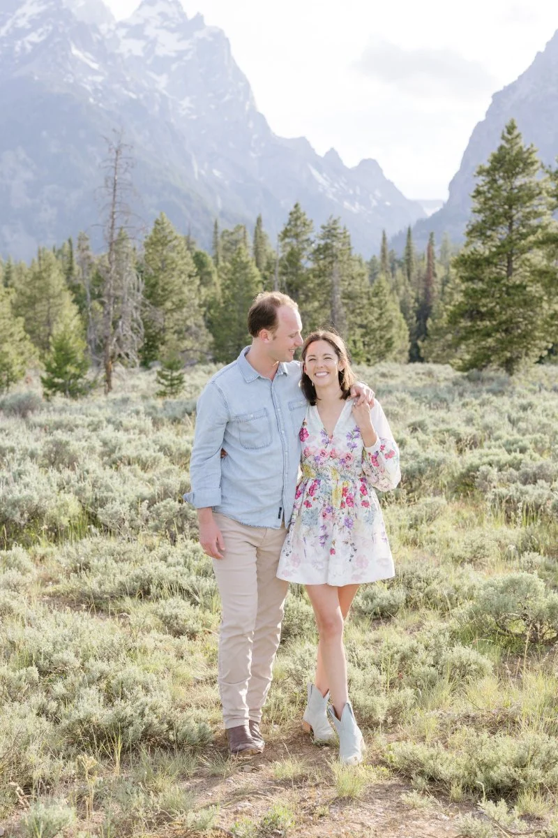  Man and woman walk together through a field during a photoshoot in Jackson Hole. 