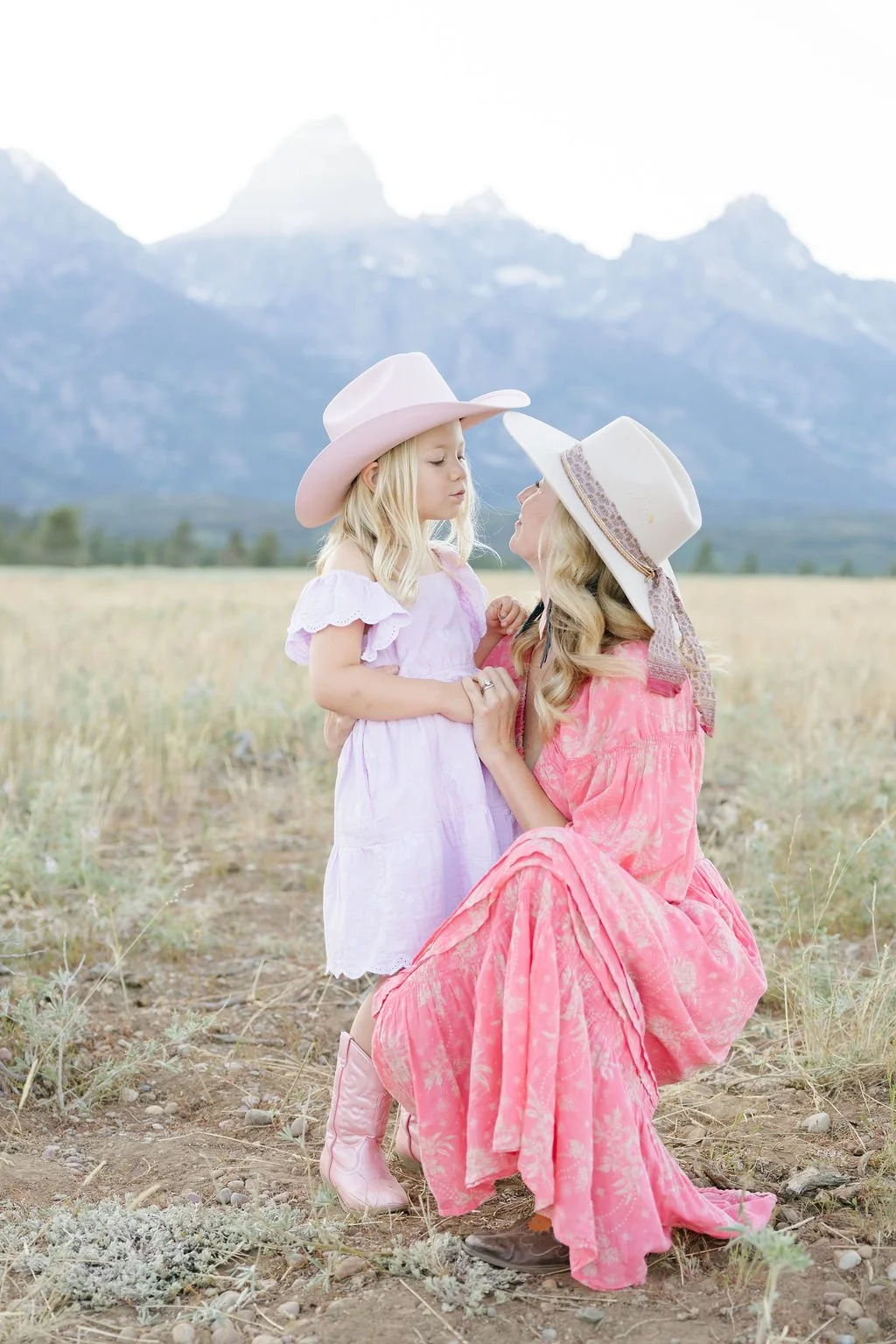  Mother and daughter sharing a sweet moment in a meadow with mountain views at Jenny Lake Grand Teton 