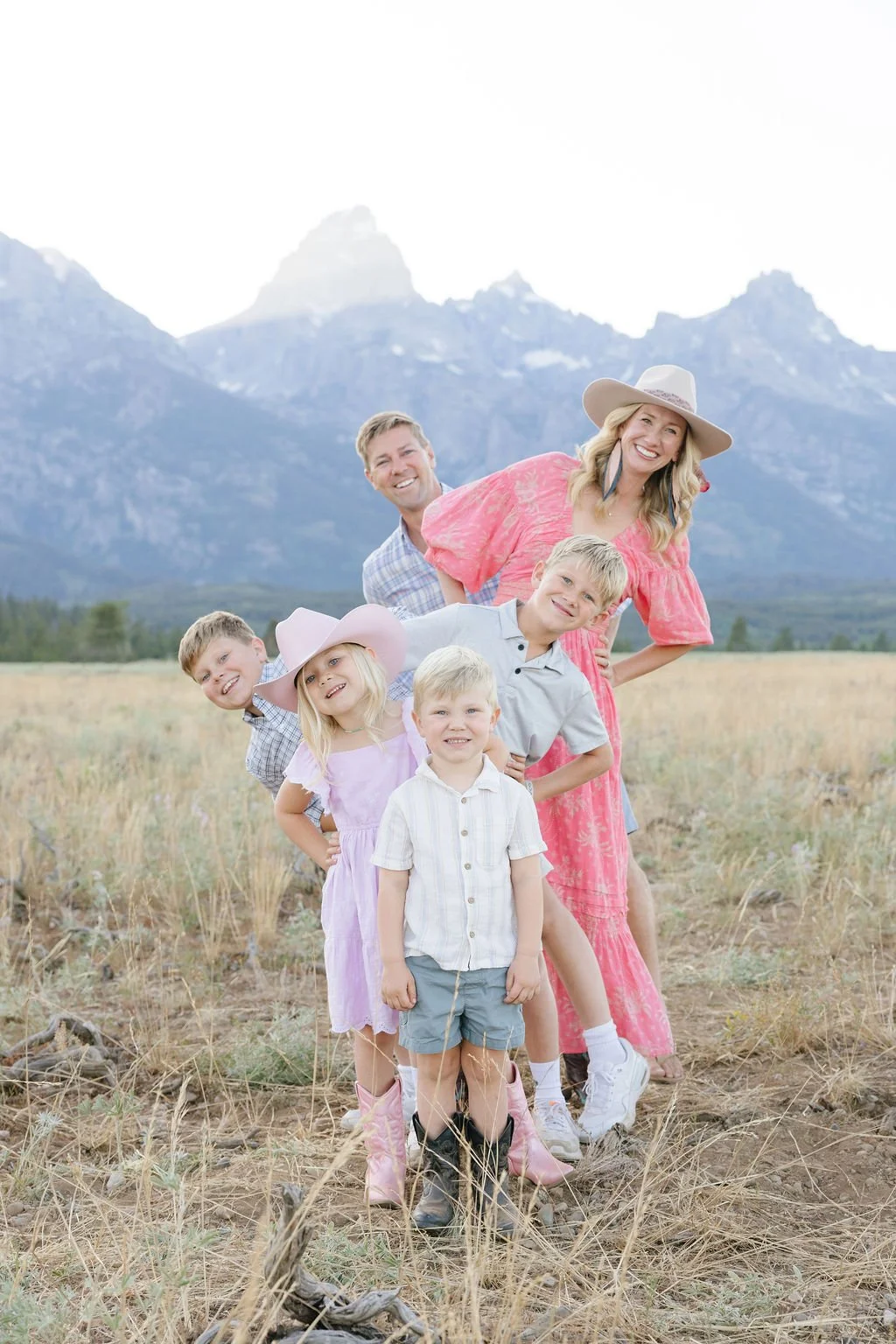  Playful family posing together in a mountain meadow with the Tetons in the background at Jenny Lake Grand Teton 