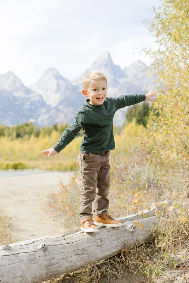  Young boy exploring near the river during Grand Teton wildflowers season in Grand Teton National Park 