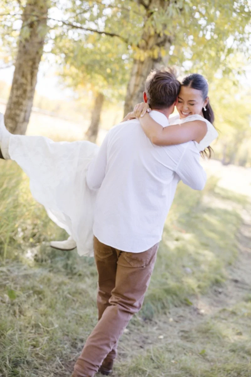  Romantic couple celebrating their engagement in Jackson Hole with playful candid moments beneath the trees 