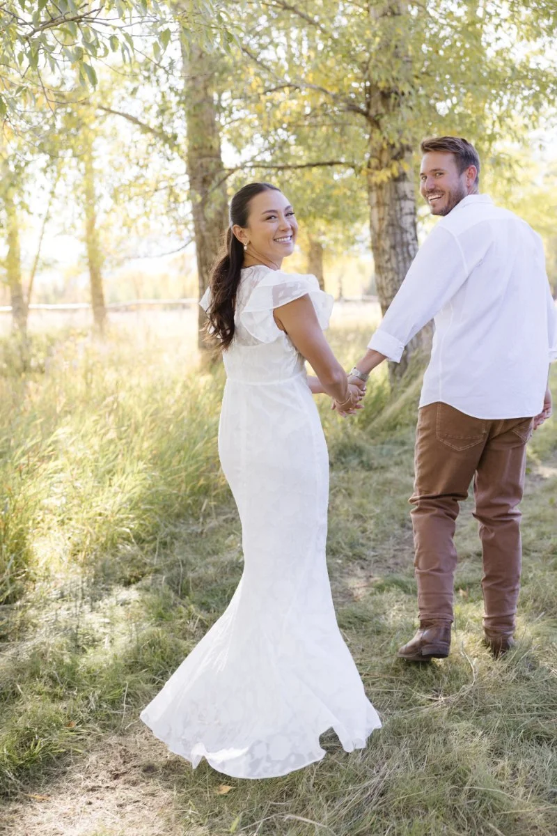  Couple walking hand in hand during their Jackson Hole engagement session surrounded by beautiful places to propose in Wyoming 