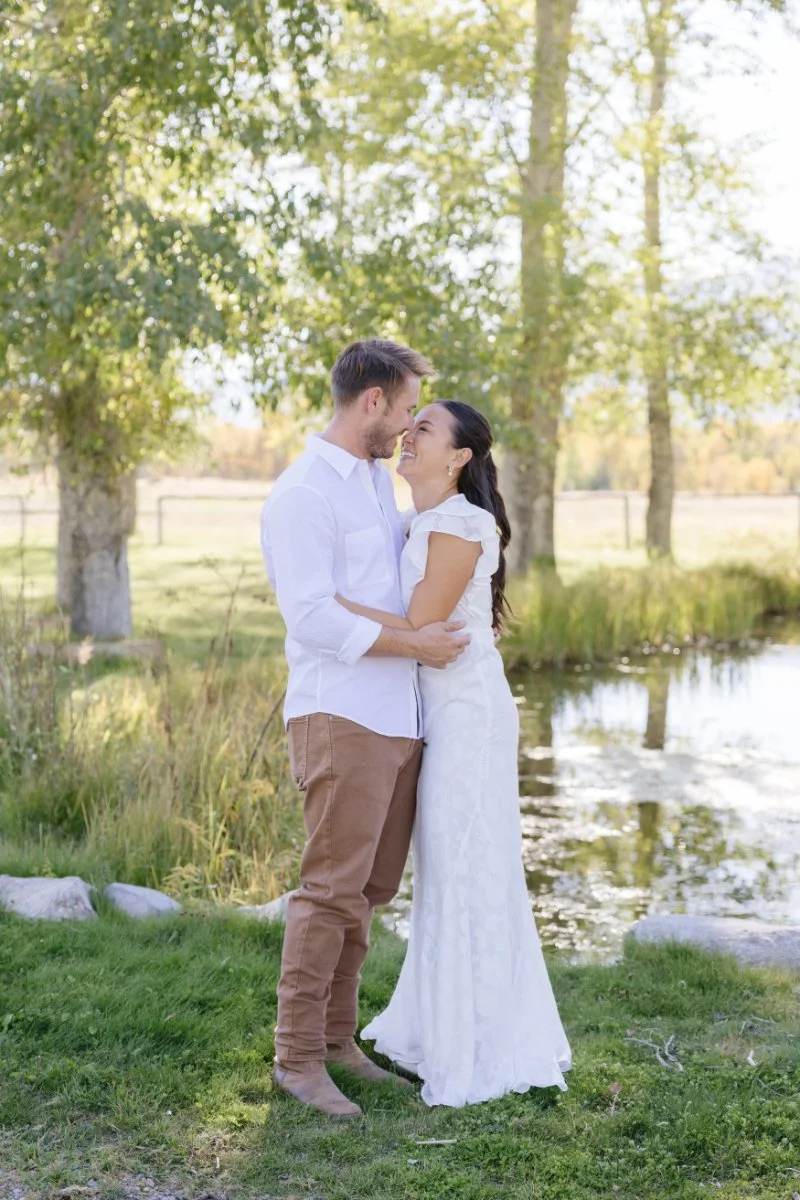  Engaged couple embracing beside a peaceful creek during a Grand Teton proposal and couples session in Jackson Hole 